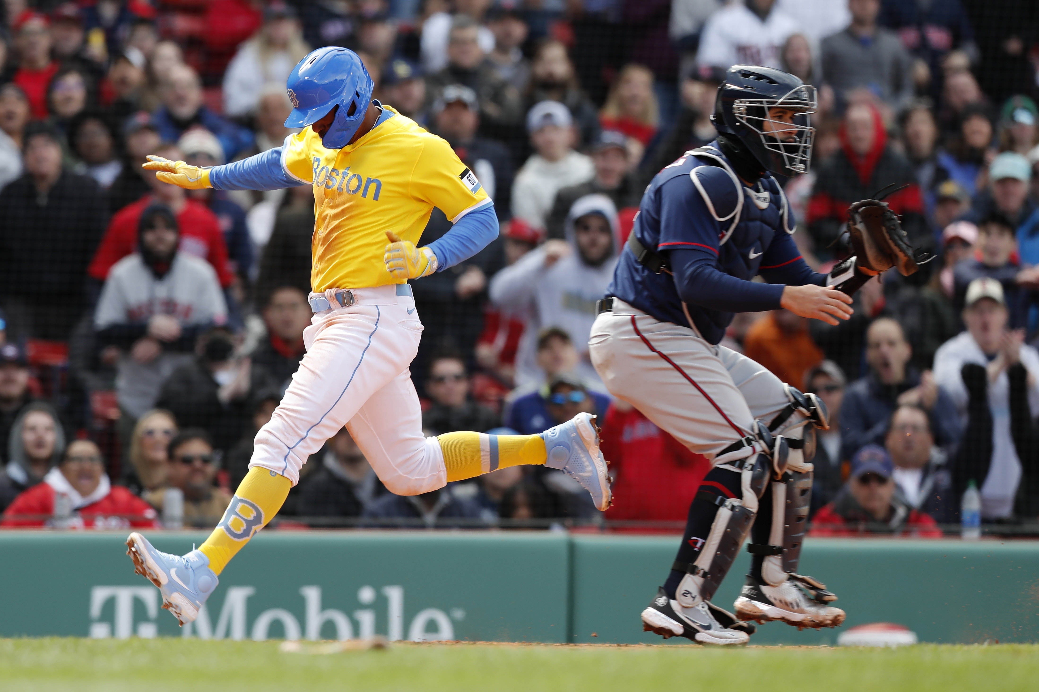Boston Red Sox's Xander Bogaerts, left, scores behind Minnesota Twins' Gary Sanchez on a sacrifice fly by Alex Verdugo during the sixth inning of a baseball game, Sunday, April 17, 2022, in Boston. 