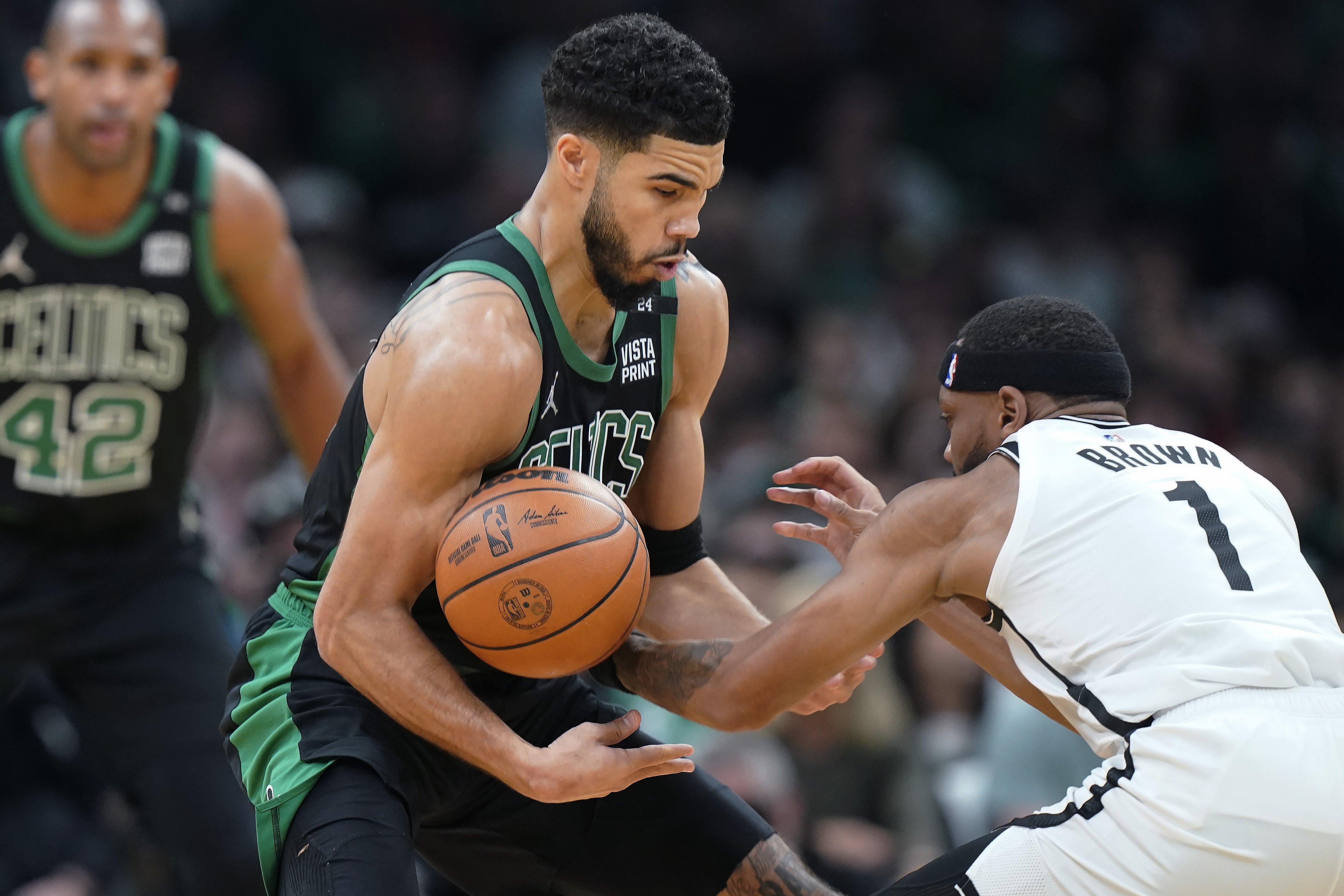 Boston Celtics forward Jayson Tatum, center, grapples for control of the ball with Brooklyn Nets forward Bruce Brown (1) in the first half of Game 1 of an NBA basketball first-round Eastern Conference playoff series, Sunday, April 17, 2022, in Boston. 