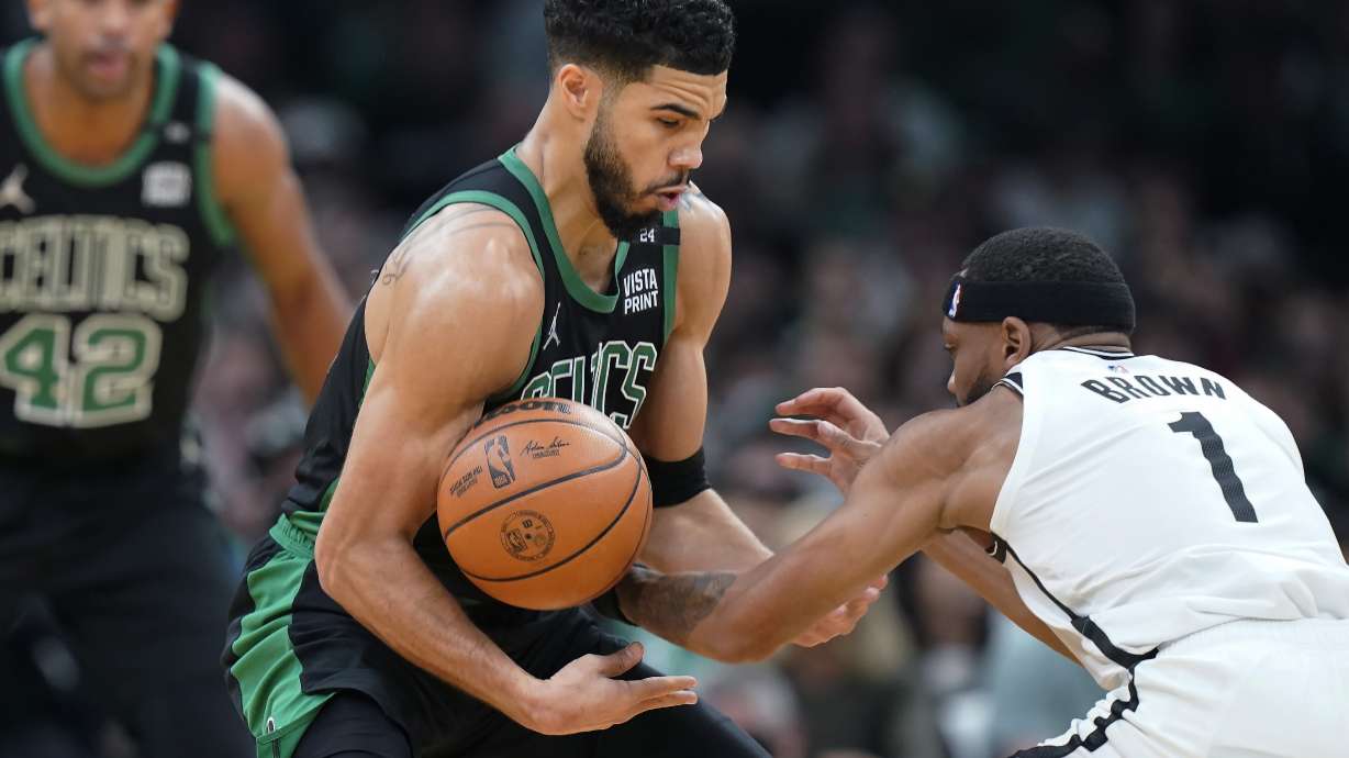 Boston Celtics forward Jayson Tatum, center, grapples for control of the ball with Brooklyn Nets forward Bruce Brown (1) in the first half of Game 1 of an NBA basketball first-round Eastern Conference playoff series, Sunday, April 17, 2022, in Boston.
