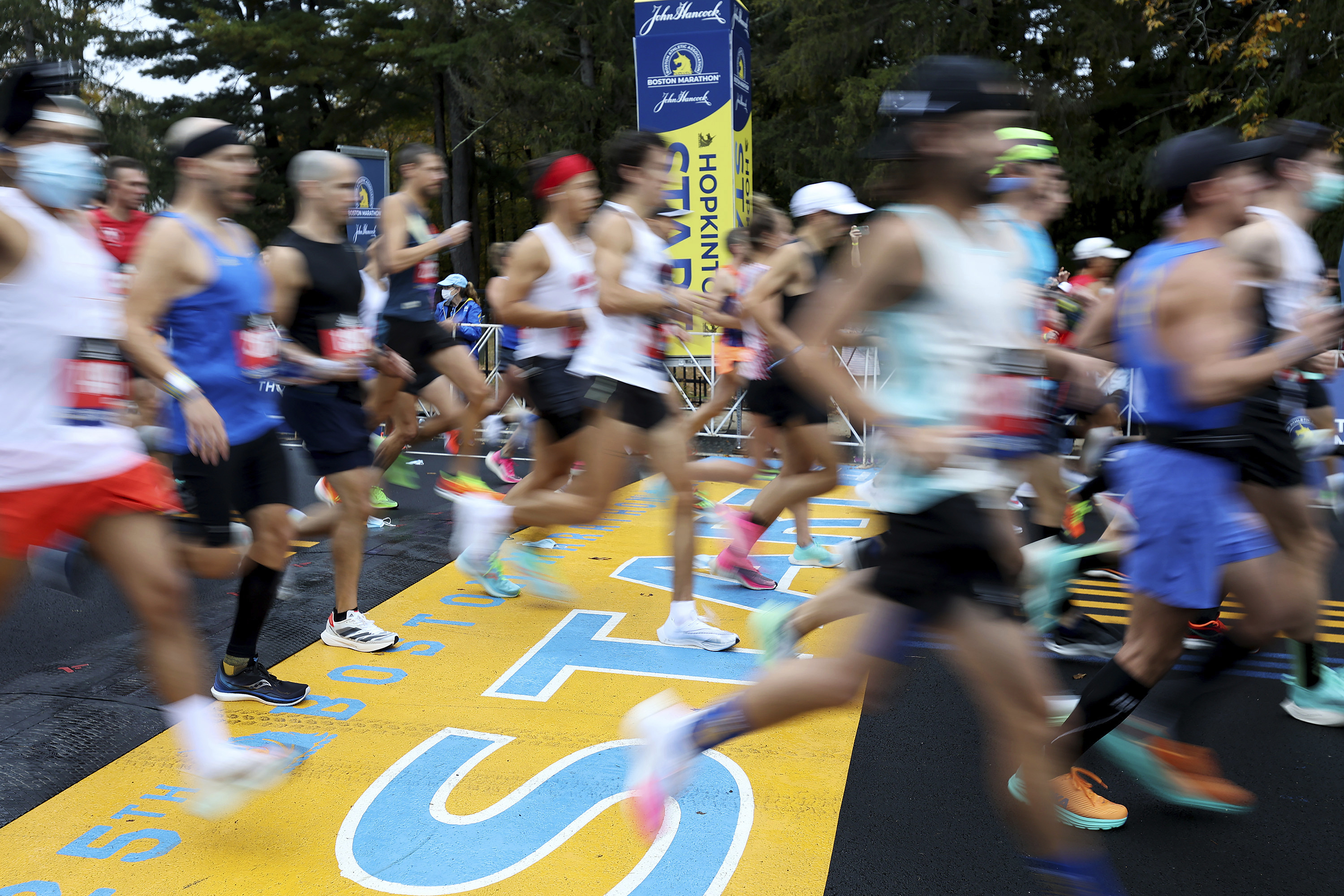 FILE - Runners cross the starting line of the 125th Boston Marathon, Monday, Oct. 11, 2021, in Hopkinton, Mass. The Boston Marathon returns, Monday, April 18, 2022. 