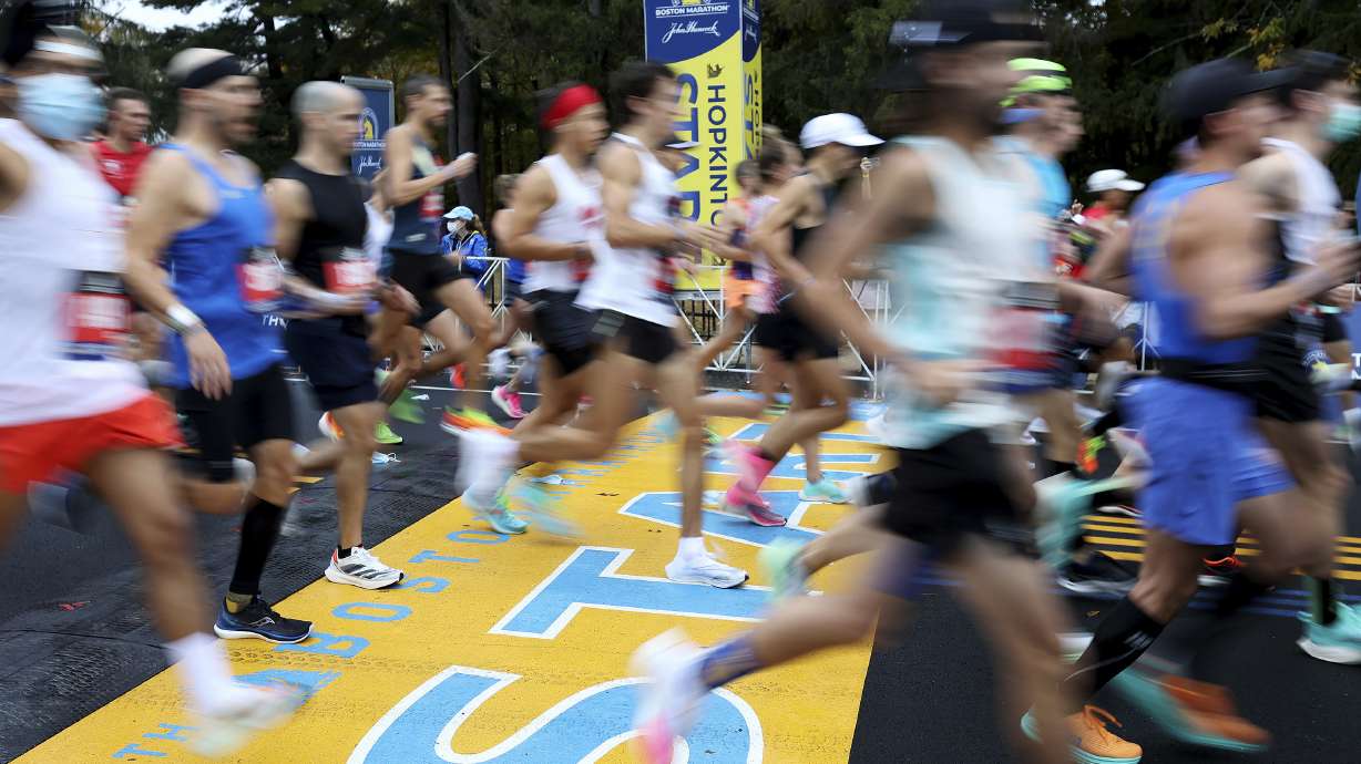 FILE - Runners cross the starting line of the 125th Boston Marathon, Monday, Oct. 11, 2021, in Hopkinton, Mass. The Boston Marathon returns, Monday, April 18, 2022.