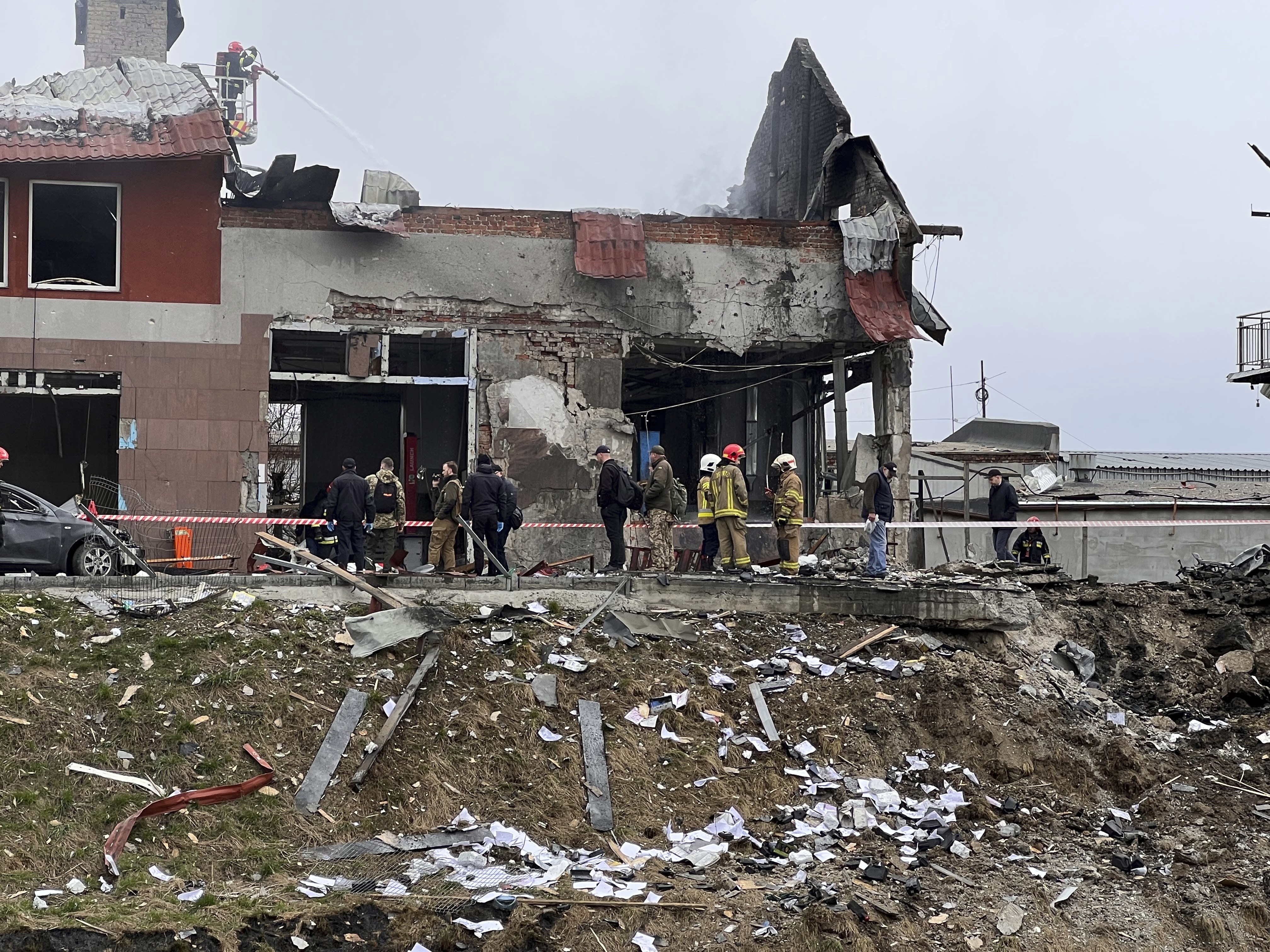 Emergency workers clear up debris after an airstrike hit a tire shop in the western city of Lviv, Ukraine, Monday.