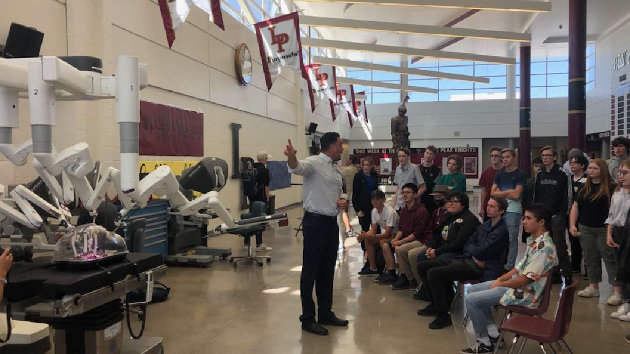 Tommy Lalli, clinical sales representative for Intuitive, prepares students to operate the da Vinci XI robotic-assisted surgical system at Lone Peak High School on Monday.