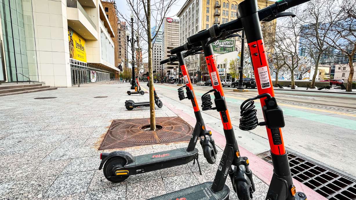 Spin e-scooters parked on Main Street in Salt Lake City on Monday. Beginning Tuesday, people can unlock Spin scooters using the Lyft app.