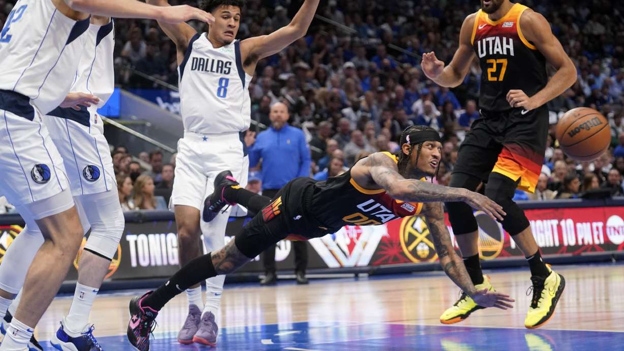 Utah Jazz guard Jordan Clarkson, center, passes the ball as he falls to the floor in front of Dallas Mavericks guard Josh Green (8) and Jazz's Rudy Gobert (27) in the first half of Game 2 of an NBA basketball first-round playoff series, Monday, April 18, 2022, in Dallas.