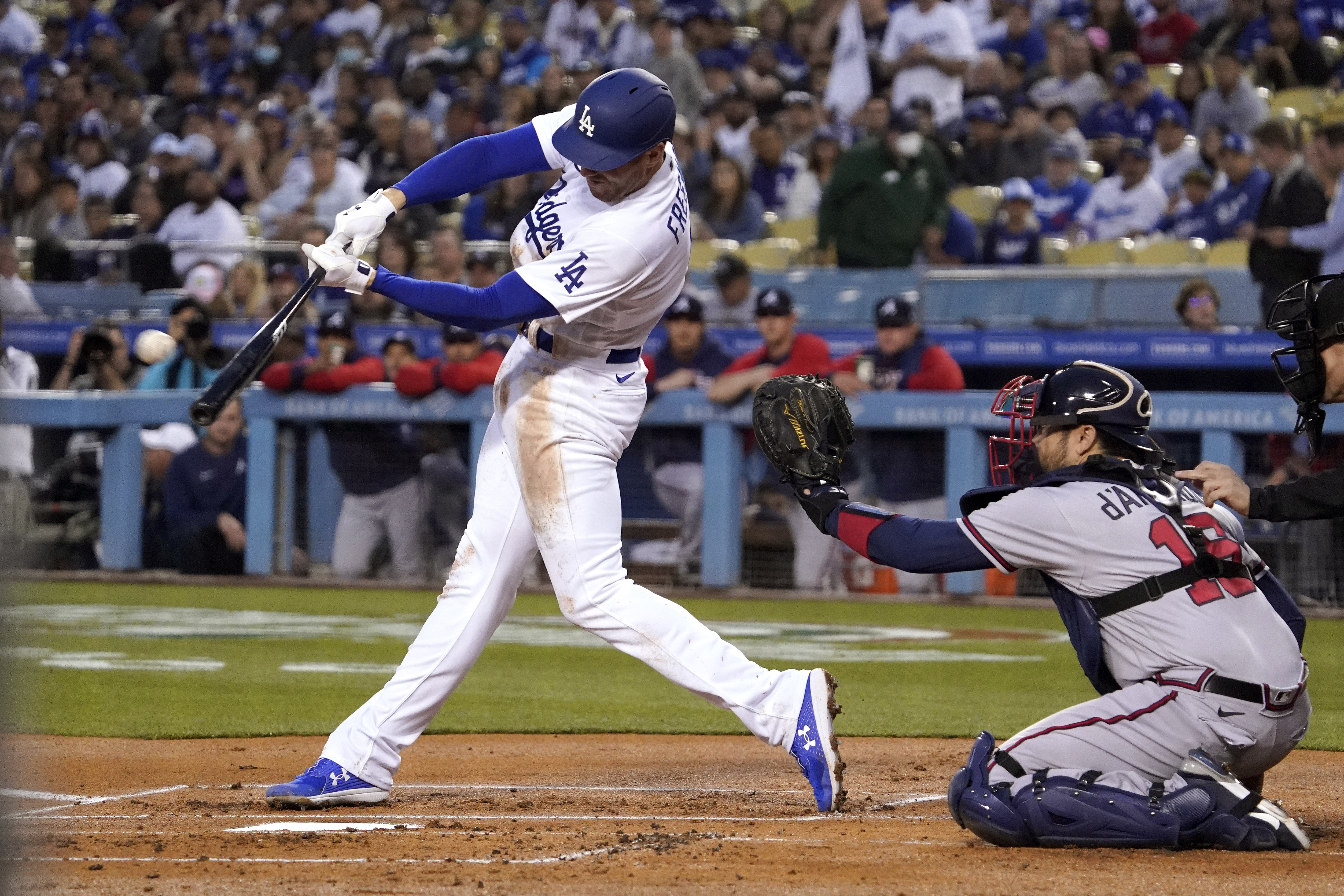 Los Angeles Dodgers' Freddie Freeman, left, hits a solo home run as Atlanta Braves catcher Travis d'Arnaud watches during the first inning of a baseball game Monday, April 18, 2022, in Los Angeles. 