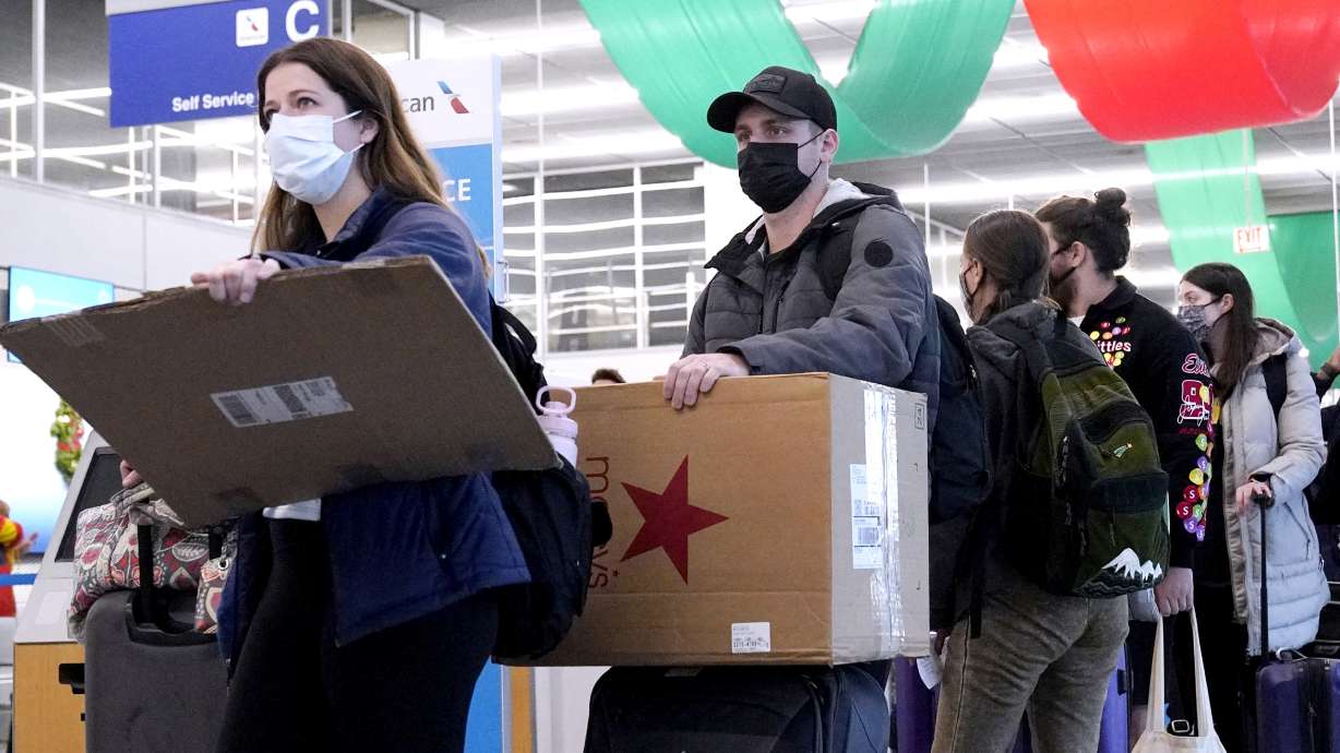 Travelers line up wearing protective masks indoors at O'Hare International Airport in Chicago, Dec. 28, 2021. On Monday, U.S. District Judge Kathryn Kimball Mizelle in Tampa, Fla., voided the national travel mask mandate as exceeding the authority of U.S. health officials.