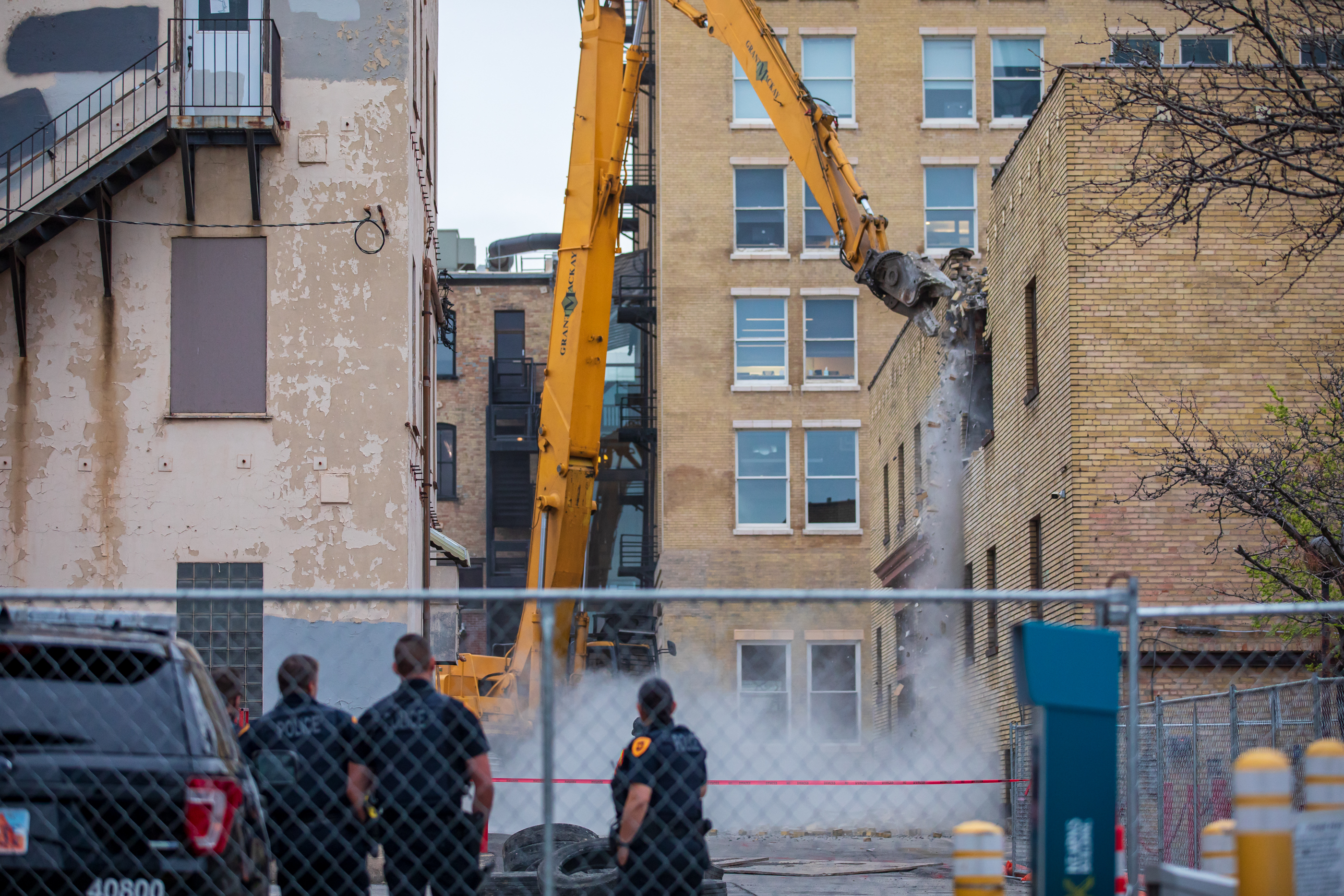 Salt Lake City police guarding the perimeter of the Utah Pantages Theater watch as demolition crews knock down an old parking garage next to the theater on April 19, 2022.