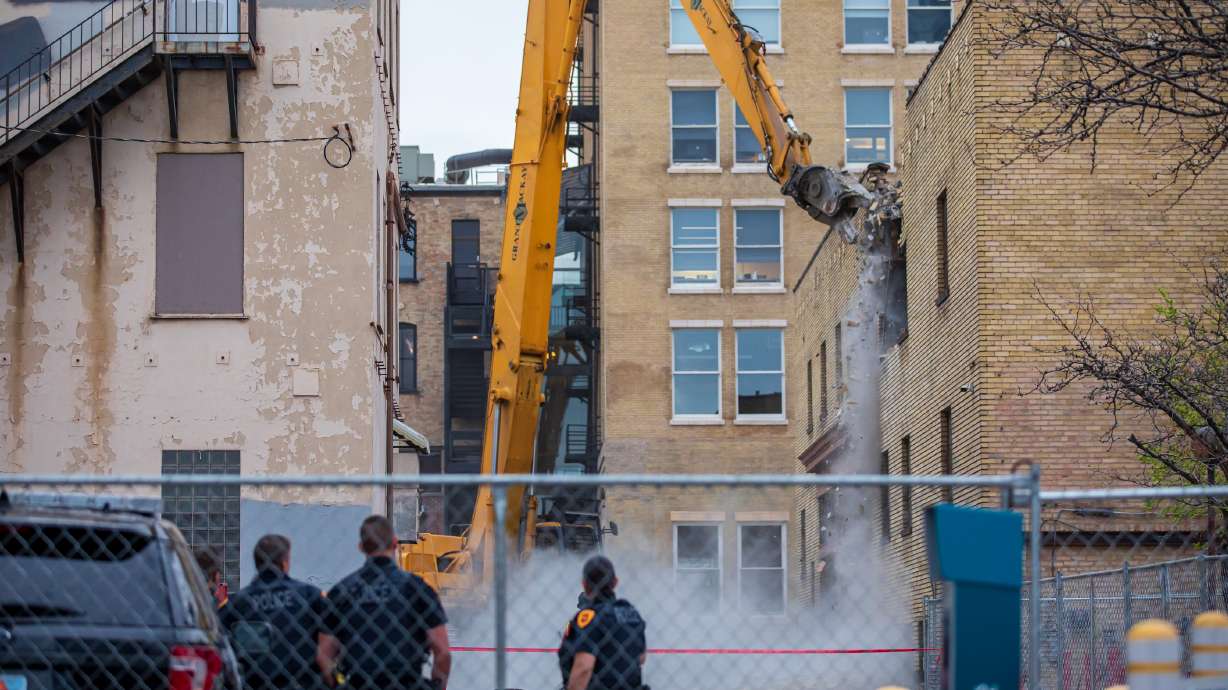 Salt Lake police guarding the perimeter of the Utah Pantages Theater watch as demolition crews knock down an old parking garage next to the theater Tuesday morning. The demolition began a day after a judge struck down a temporary restraining order to protect the theater.
