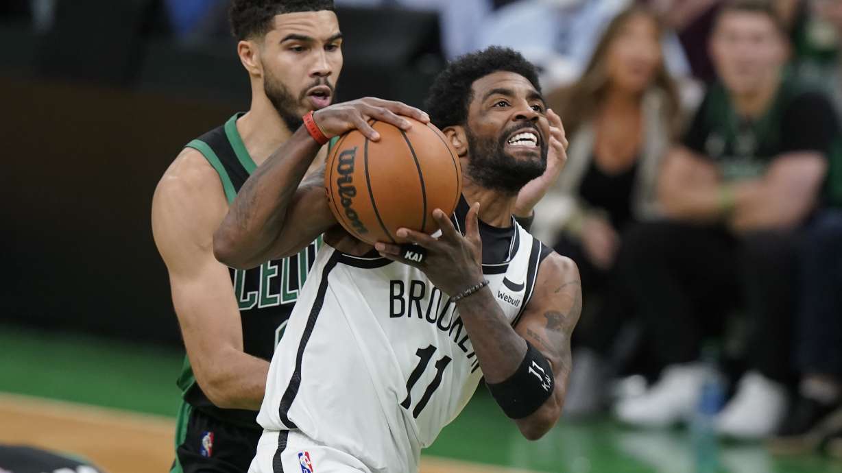 Brooklyn Nets guard Kyrie Irving (11) drives toward the basket as Boston Celtics forward Jayson Tatum (0) defends in the second half of Game 1 of an NBA basketball first-round Eastern Conference playoff series, Sunday, April 17, 2022, in Boston. The Celtics won 115-114.