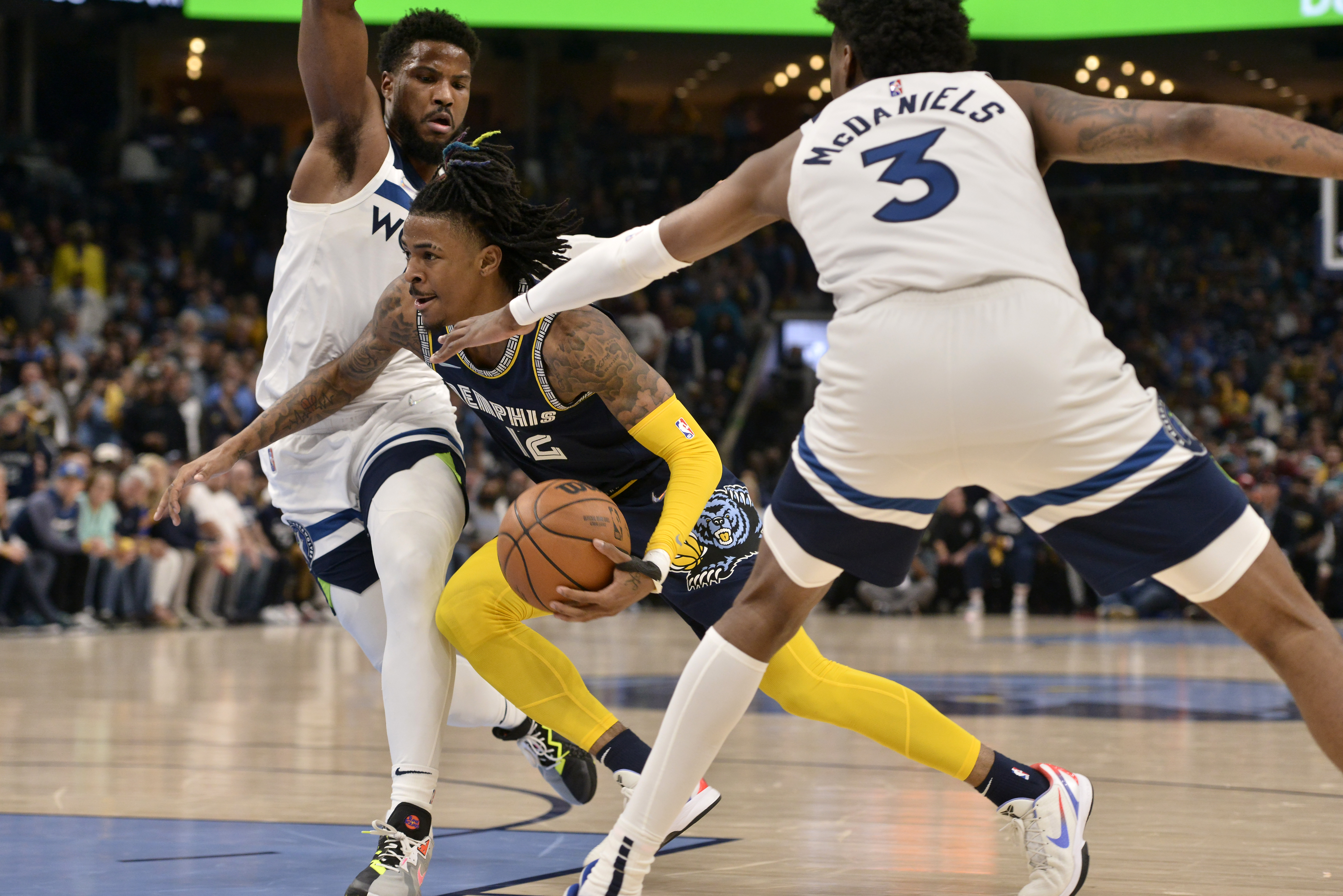 Memphis Grizzlies guard Ja Morant (12) drives between Minnesota Timberwolves forward Jaden McDaniels (3) and guard Malik Beasley (5) during the first half of Game 2 of a first-round NBA basketball playoff series Tuesday, April 19, 2022, in Memphis, Tenn. 