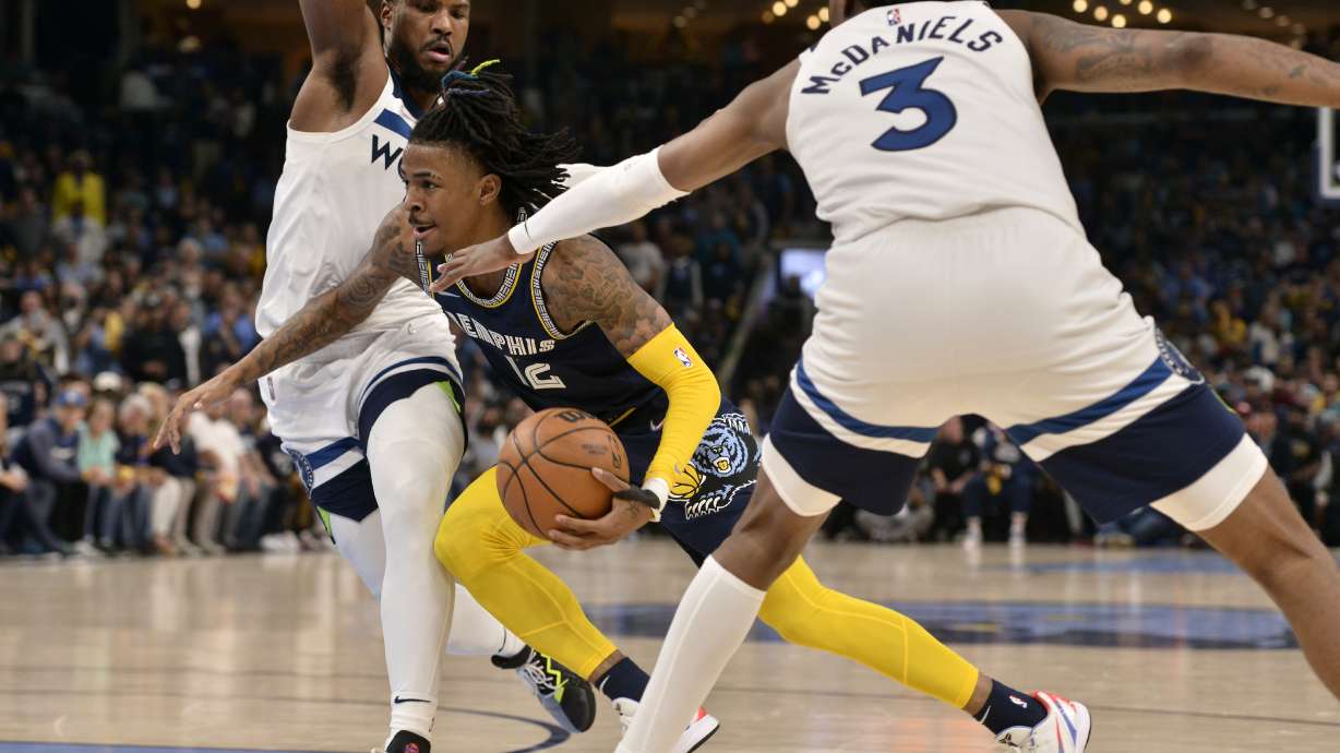 Memphis Grizzlies guard Ja Morant (12) drives between Minnesota Timberwolves forward Jaden McDaniels (3) and guard Malik Beasley (5) during the first half of Game 2 of a first-round NBA basketball playoff series Tuesday, April 19, 2022, in Memphis, Tenn.