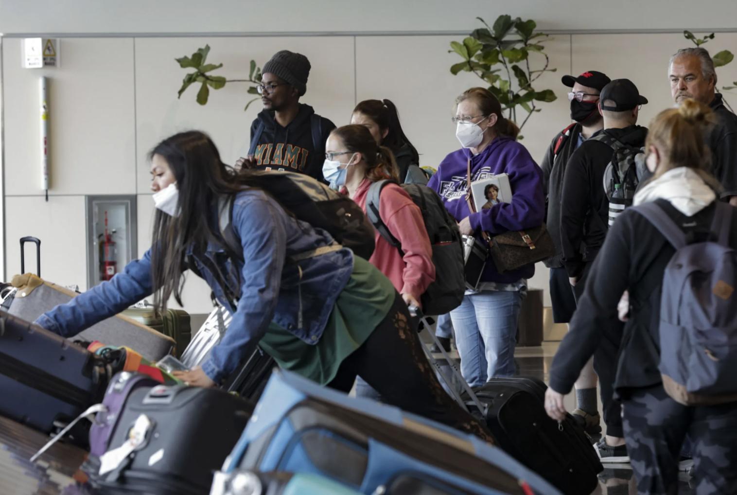 Masked and unmasked travelers wait for their luggage at the Salt Lake City International Airport in Salt Lake City on Tuesday. A federal judge in Florida struck down the mask requirement on public transportation on Monday.