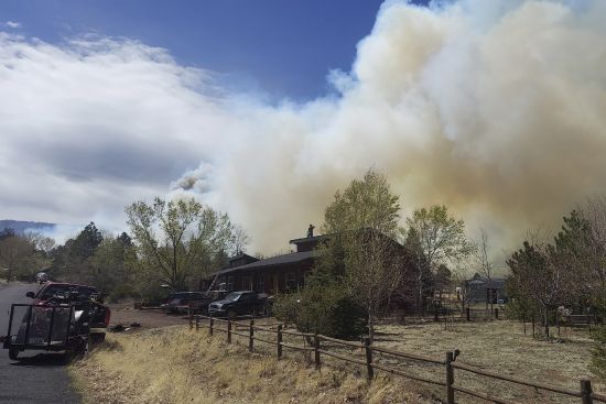 Smoke from a wind-whipped wildfire rises above neighborhoods on the outskirts of Flagstaff, Ariz., on Tuesday. Homes on the outskirts of Flagstaff were being evacuated Tuesday as high winds whipped a wildfire, shut down a major highway and grounded firefighting aircraft.
