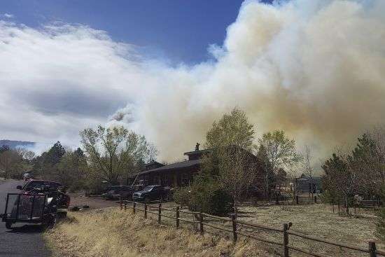 Smoke from a wind-whipped wildfire rises above neighborhoods on the outskirts of Flagstaff, Ariz., on Tuesday. Homes on the outskirts of Flagstaff were being evacuated Tuesday as high winds whipped a wildfire, shut down a major highway and grounded firefighting aircraft.