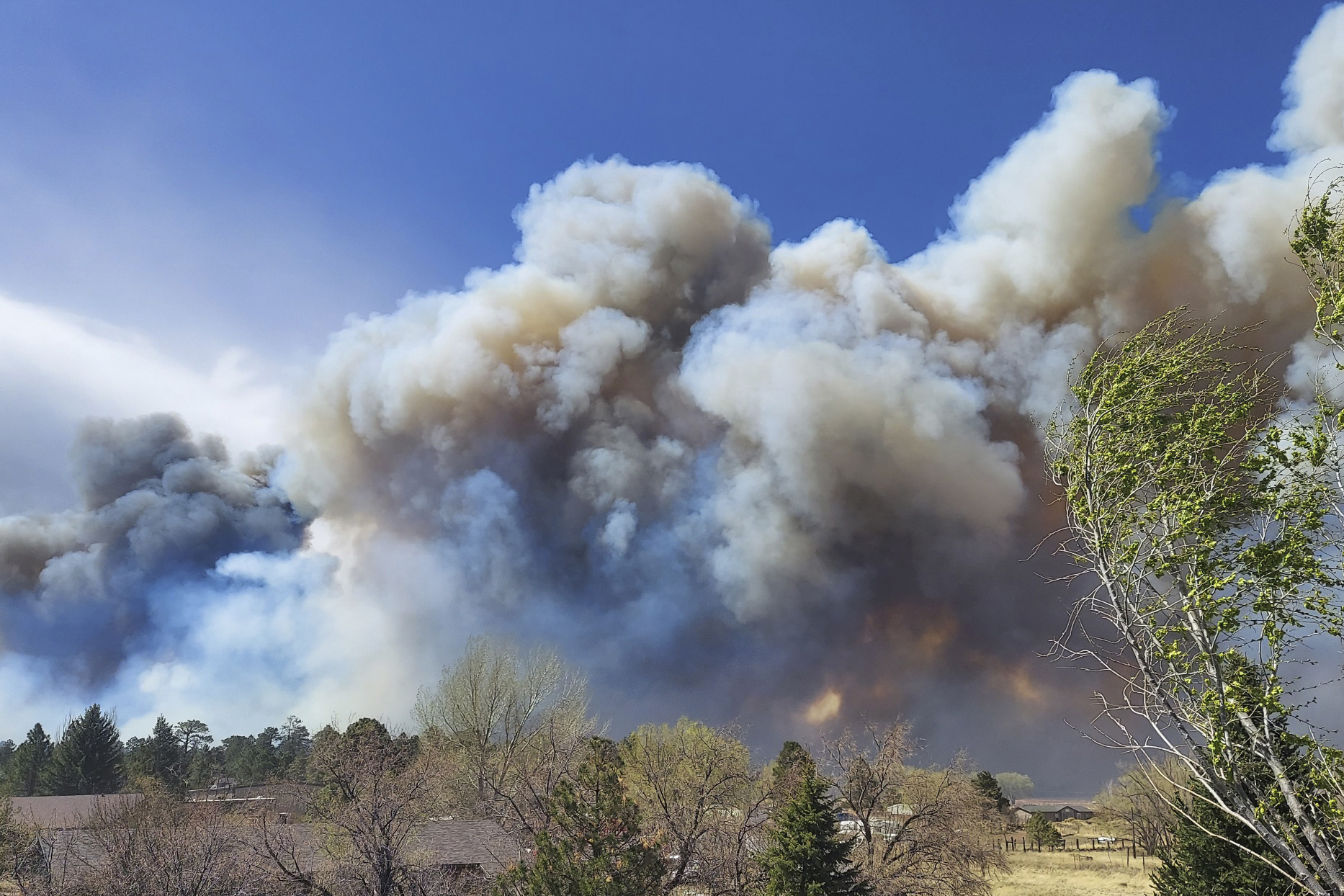 Smoke from a wind-whipped wildfire rises above neighborhoods on the outskirts of Flagstaff, Ariz., on Tuesday. Homes on the outskirts of Flagstaff were being evacuated Tuesday as high winds whipped a wildfire, shut down a major highway and grounded firefighting aircraft. 