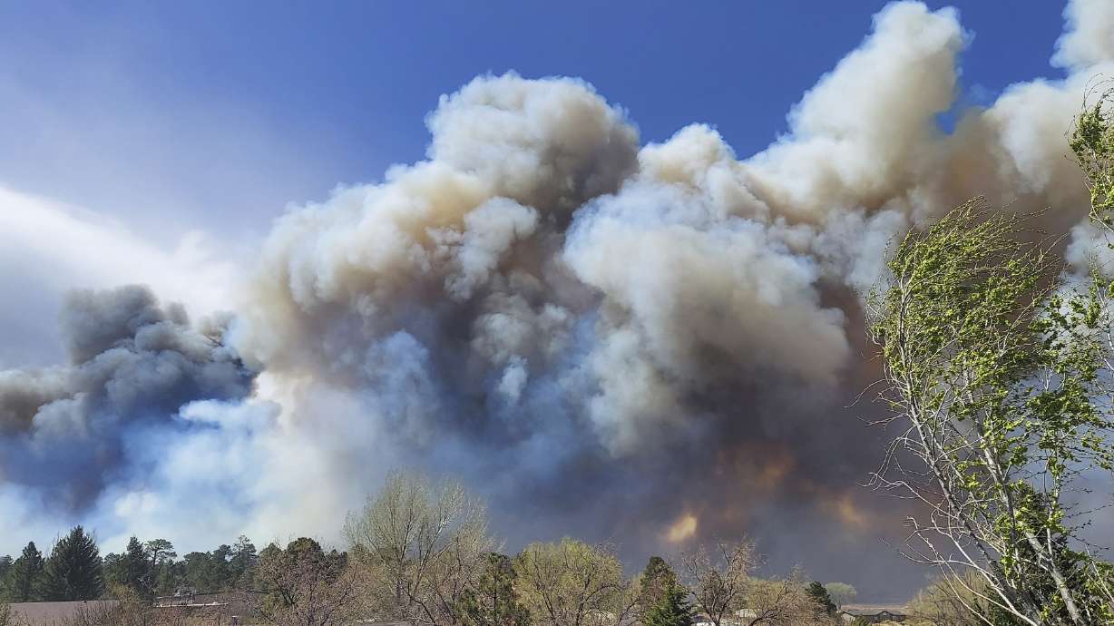Smoke from a wind-whipped wildfire rises above neighborhoods on the outskirts of Flagstaff, Ariz., on Tuesday. Homes on the outskirts of Flagstaff were being evacuated Tuesday as high winds whipped a wildfire, shut down a major highway and grounded firefighting aircraft.