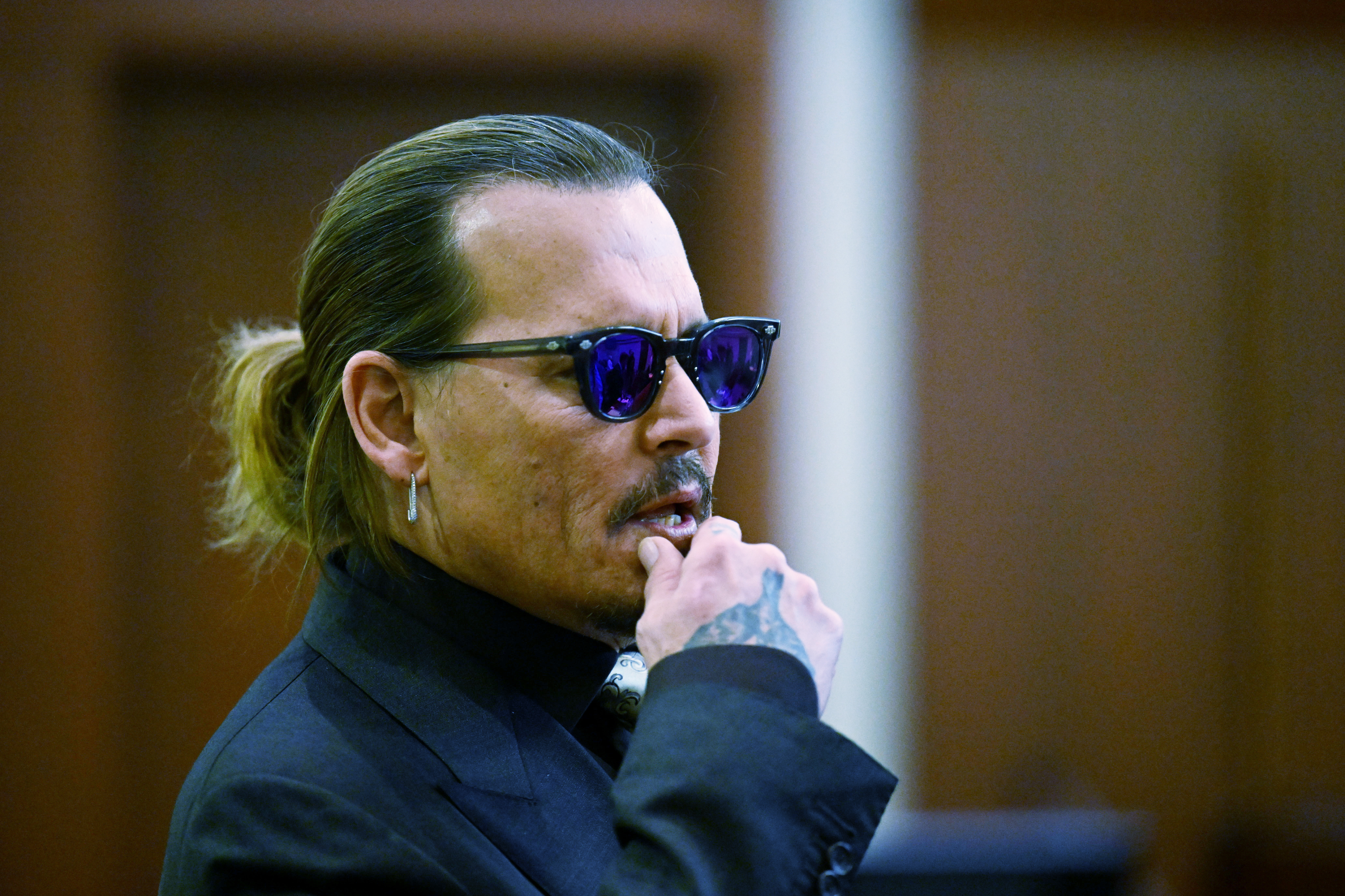 Actor Johnny Depp listens during a hearing at the Fairfax County Circuit Court in Fairfax, Va., Tuesday. Wednesday Depp scoffed at the notion during court testimony that his constant quarrels with ex-wife Amber Heard would ever prompt him to hit her. 