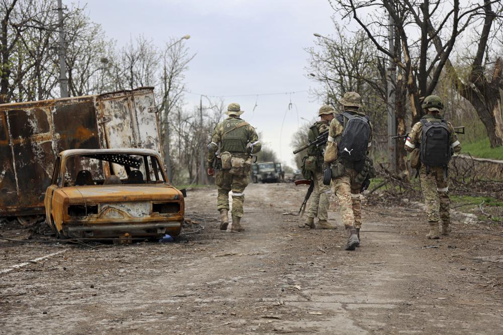 Servicemen of Donetsk People's Republic militia walk past damaged vehicles in Mariupol, Ukraine, Tuesday. Russia taking Mariupol would deprive Ukraine of a vital port and complete a land bridge between Russia and the Crimean Peninsula.