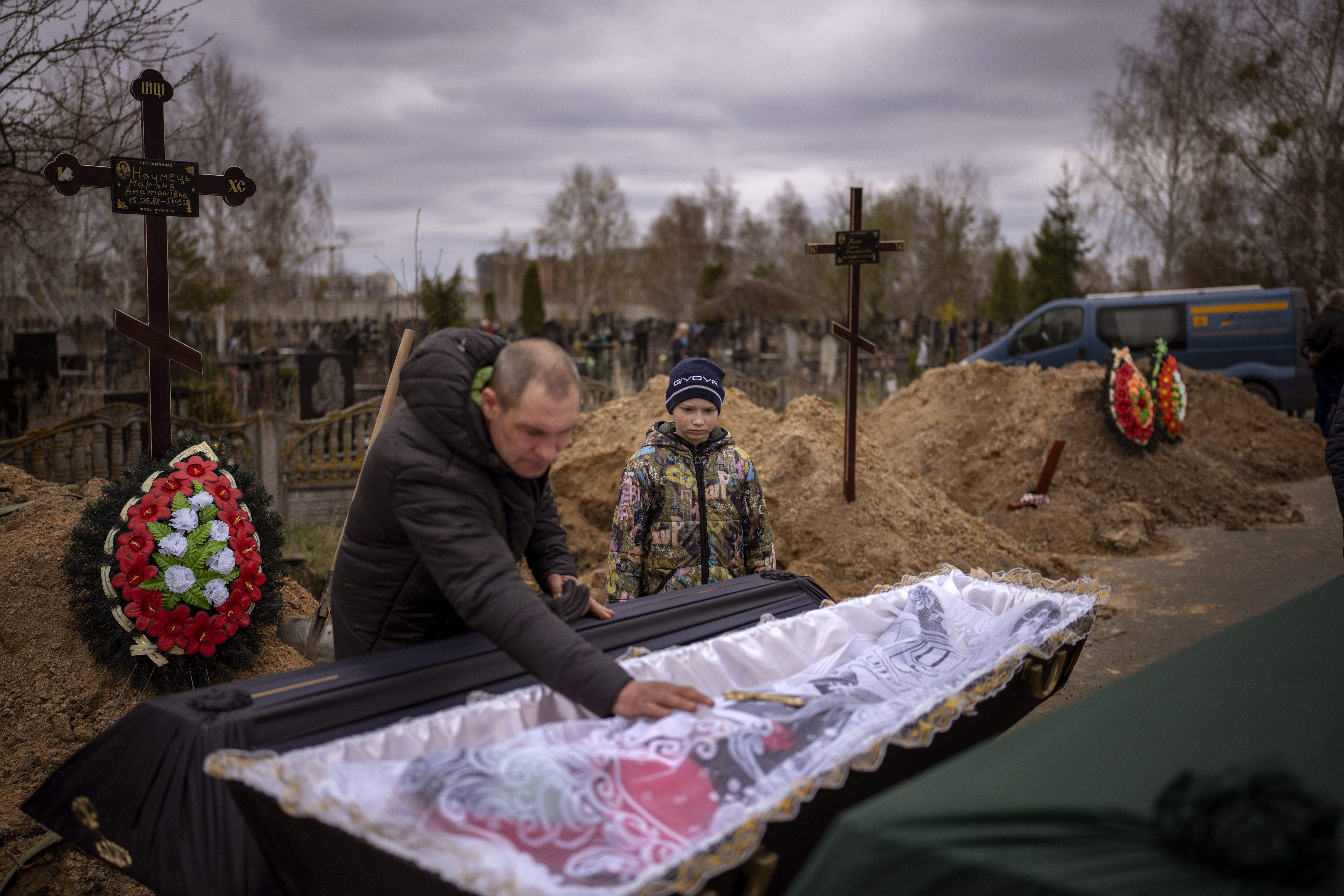 Vova, 10, looks at the body of his mother, Maryna, lying in a coffin as his father, Ivan Drahun, prays during her funeral in Bucha, on the outskirts of Kyiv, Ukraine, on Wednesday. Vova’s mother died while they sheltered in a cold basement for more than a month during the Russian military’s occupation.