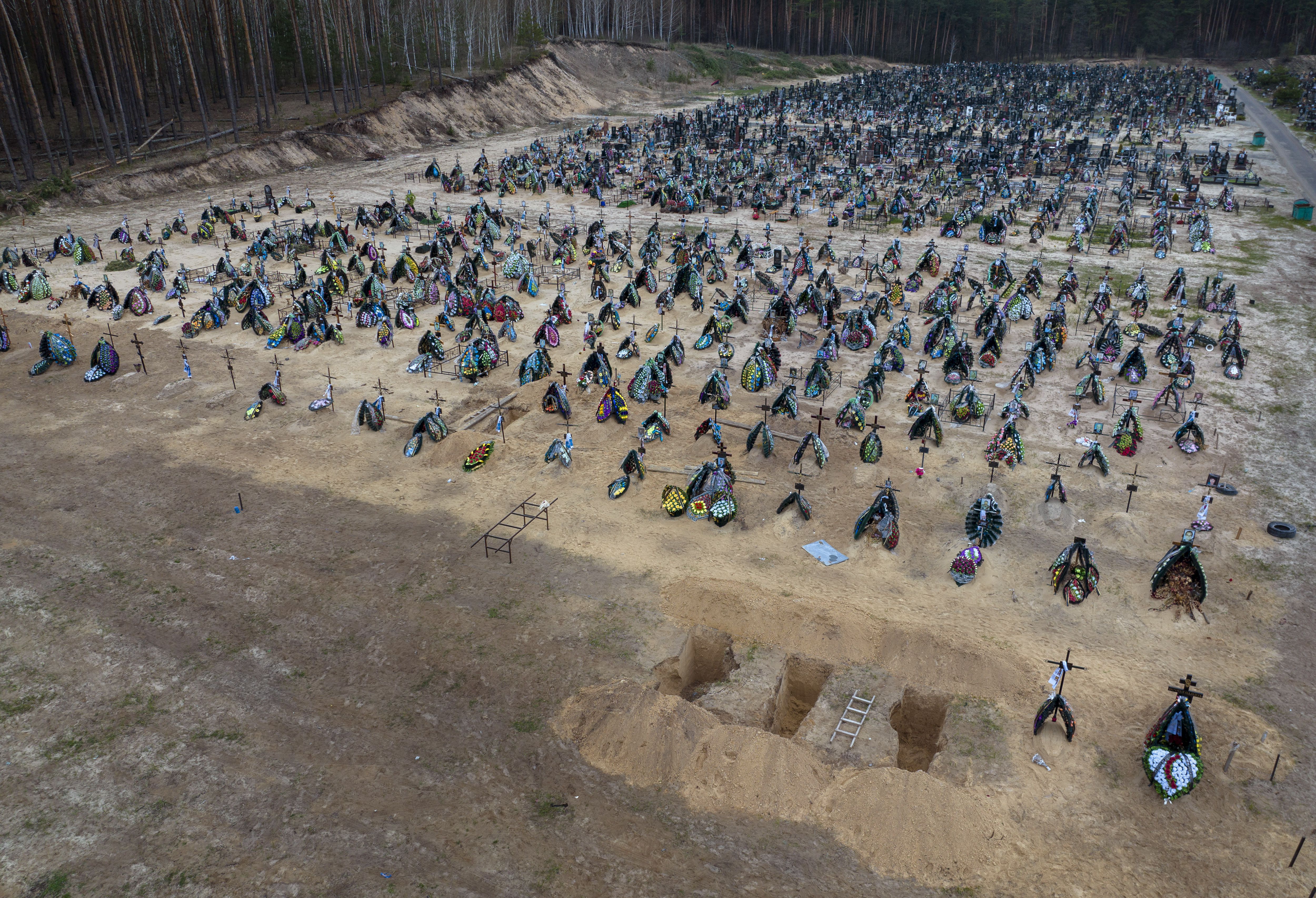 Three dug graves are ready for the next funerals at the cemetery in Irpin, on the outskirts of Kyiv, Ukraine, Tuesday.