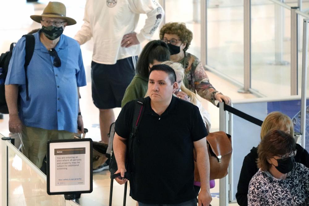 Travelers wait in a security line at Love Field in Dallas, Tuesday. A majority of Americans continue to support a mask requirement for people traveling on airplanes and other shared transportation, a new poll finds.