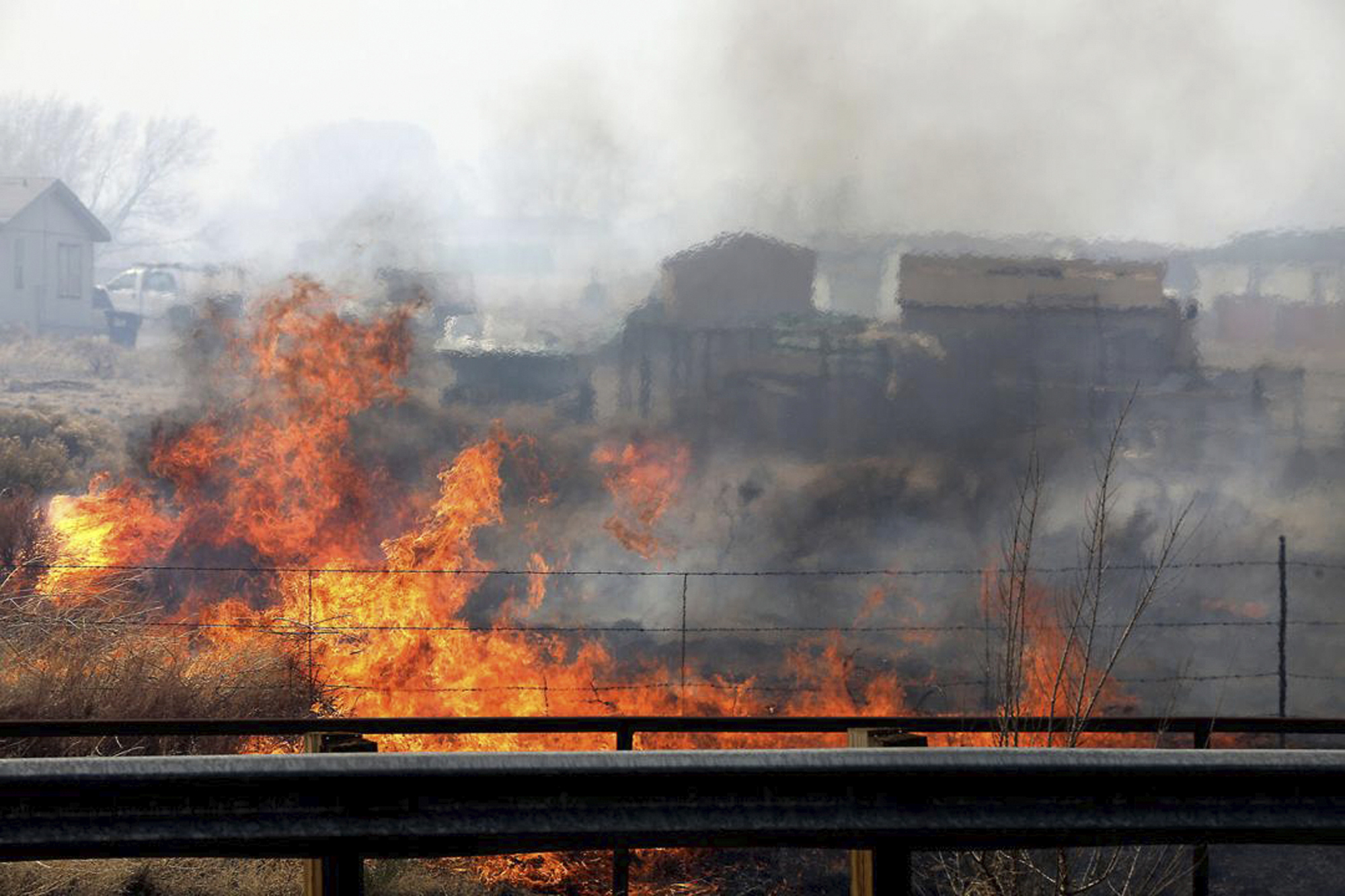 A wind-driven wildfire burns at the edge of U.S. 89 on the outskirts of Flagstaff, Ariz., on Tuesday. An Arizona wildfire doubled in size overnight into Wednesday, a day after heavy winds kicked up a towering wall of flames outside a northern Arizona tourist and college town, ripping through two dozen structures and sending residents of more than 700 homes scrambling to flee.