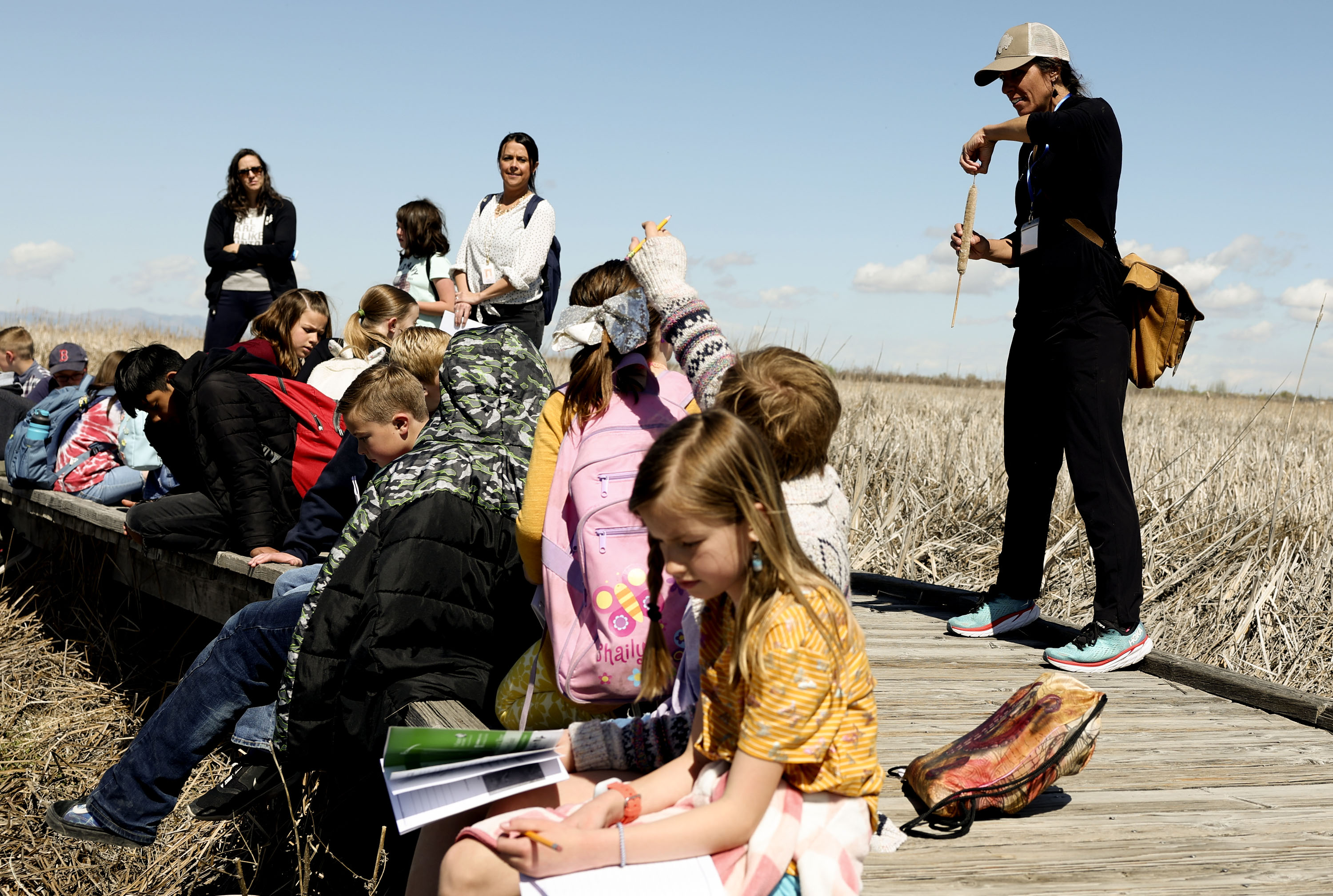 Volunteer naturalist Kristen Bonner, right, shows Creekside Elementary students a cattail at the Great Salt Lake Shorelands Preserve as part of The Nature Conservancy's Wings & Water program in Layton on Wednesday.
