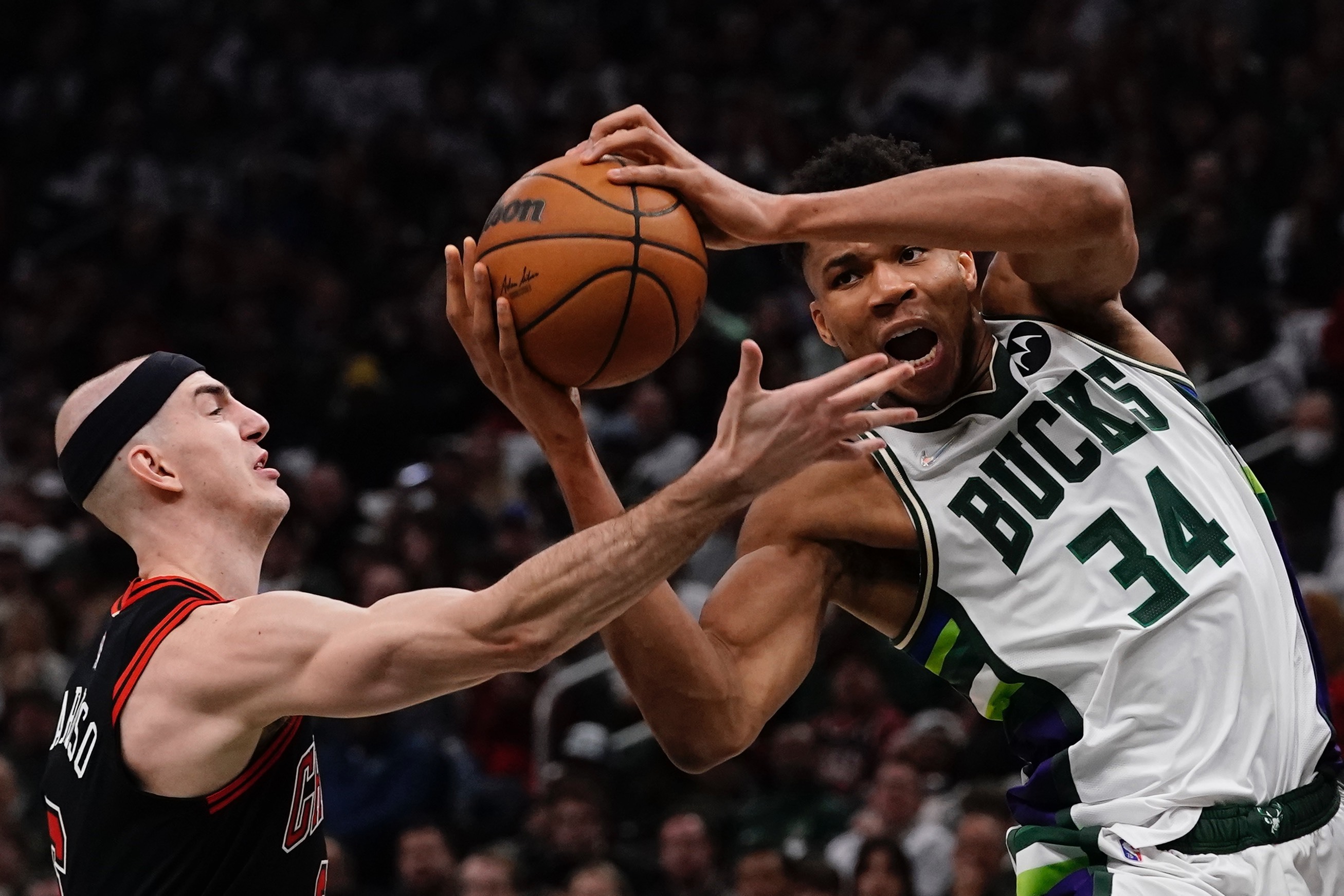 Milwaukee Bucks' Giannis Antetokounmpo and Chicago Bulls' Alex Caruso go for the ball during the first half of Game 2 of their an NBA playoff basketball game Wednesday, April 20, 2022, in Milwaukee . 
