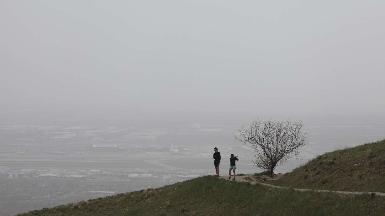 The west side of the Salt Lake Valley is barely visible as joggers make their way across the Bonneville Shoreline Trail on a windy day in Salt Lake City on Thursday.