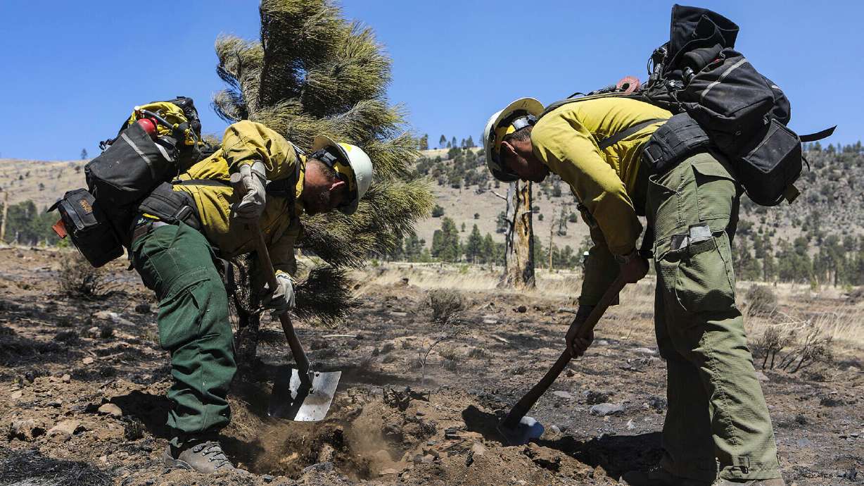 Two firefighters monitor hot spots from a wildfire burning on the outskirts of Flagstaff, Ariz., Thursday. Authorities on Friday say 30 homes were burned when a wind-driven wildfire ripped though neighborhoods near Flagstaff, Ariz., on Tuesday.