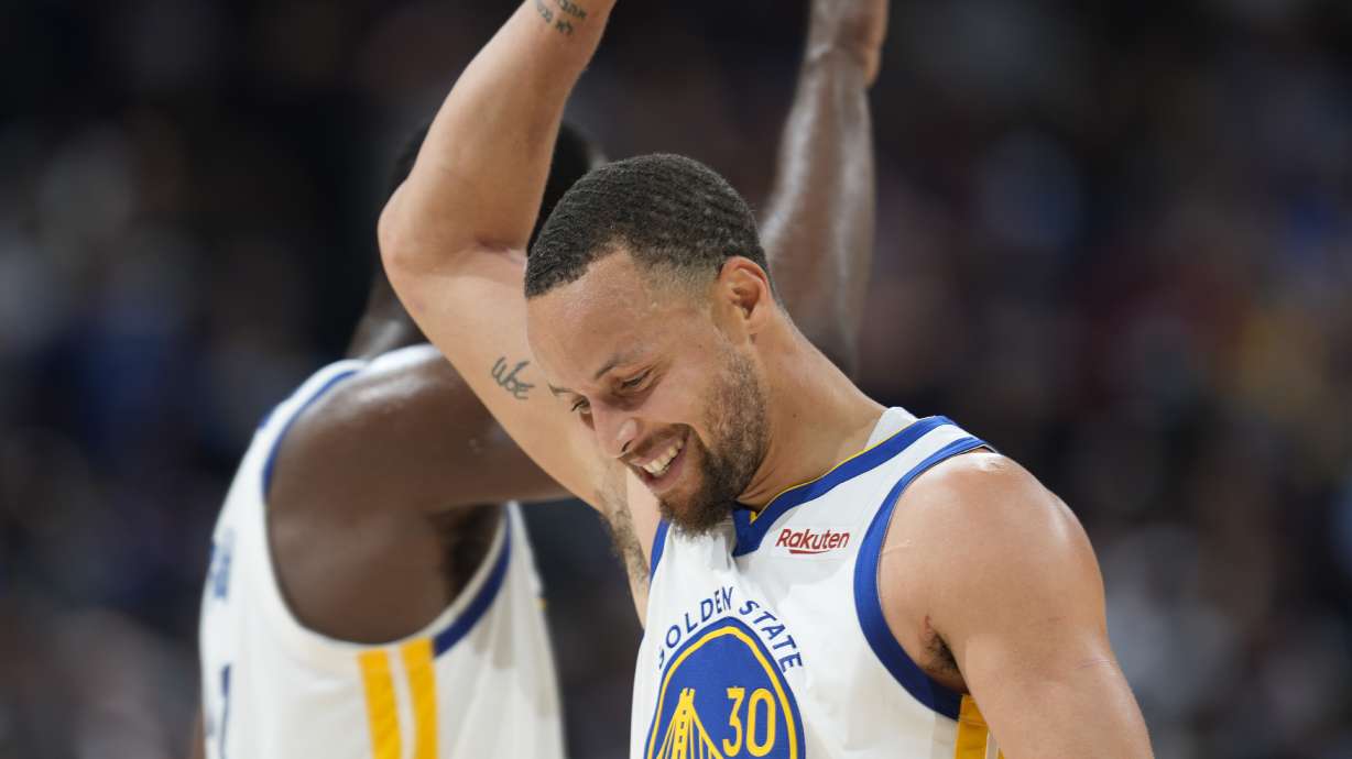 Golden State Warriors guard Stephen Curry, front, congratulates forward Draymond Green near the endoof Game 3 of the team's NBA basketball first-round Western Conference playoff series against the Denver Nuggets Thursday, April 21, 2022, in Denver.