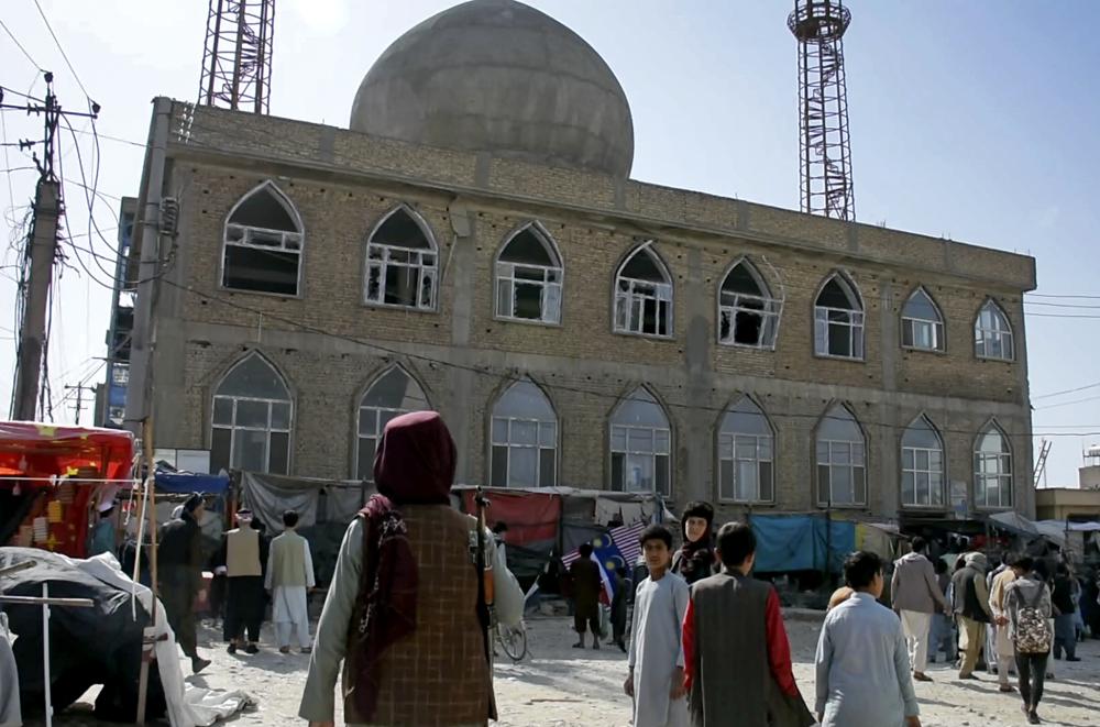 This frame grab image from video, shows a Taliban fighter standing guard outside the site of a bomb explosion inside a mosque, in Mazar-e-Sharif province, Afghanistan, Thursday. A Taliban official says the bombing in northern Afghanistan on Friday killed at least 33 people