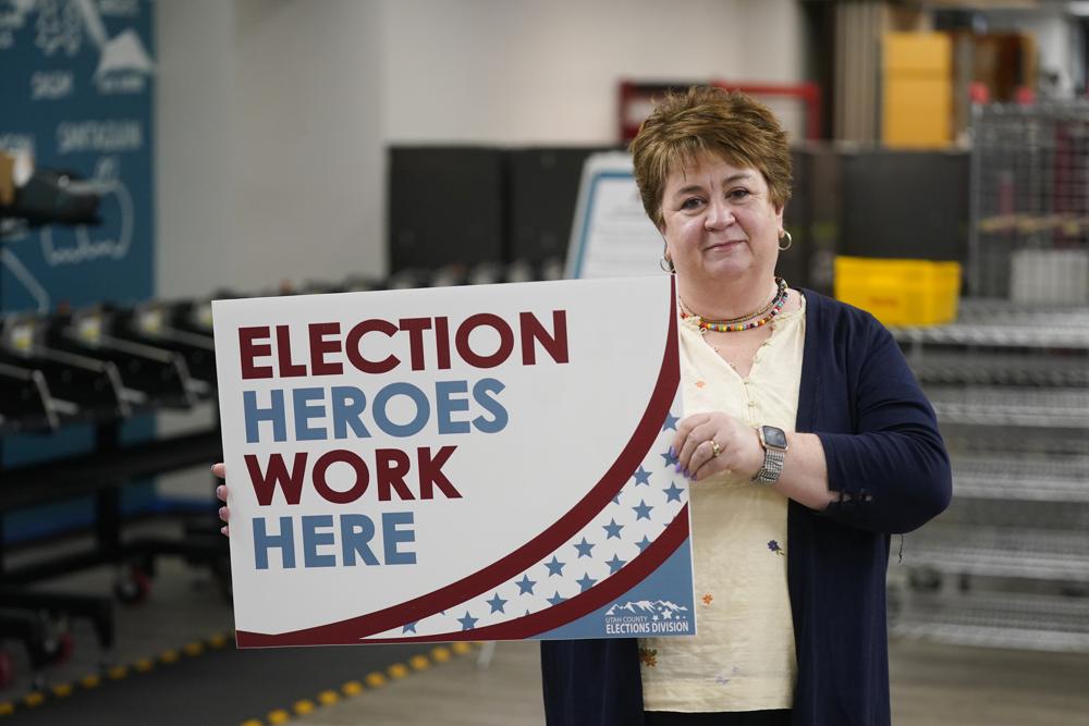 Utah County elections director Rozan Mitchell holds a "Election Heroes Work Here" sign during a tour of Utah County's elections equipment and review processes for administering secure elections Tuesday in Provo, Utah. Mail-in voting is under greater scrutiny since the 2020 election.