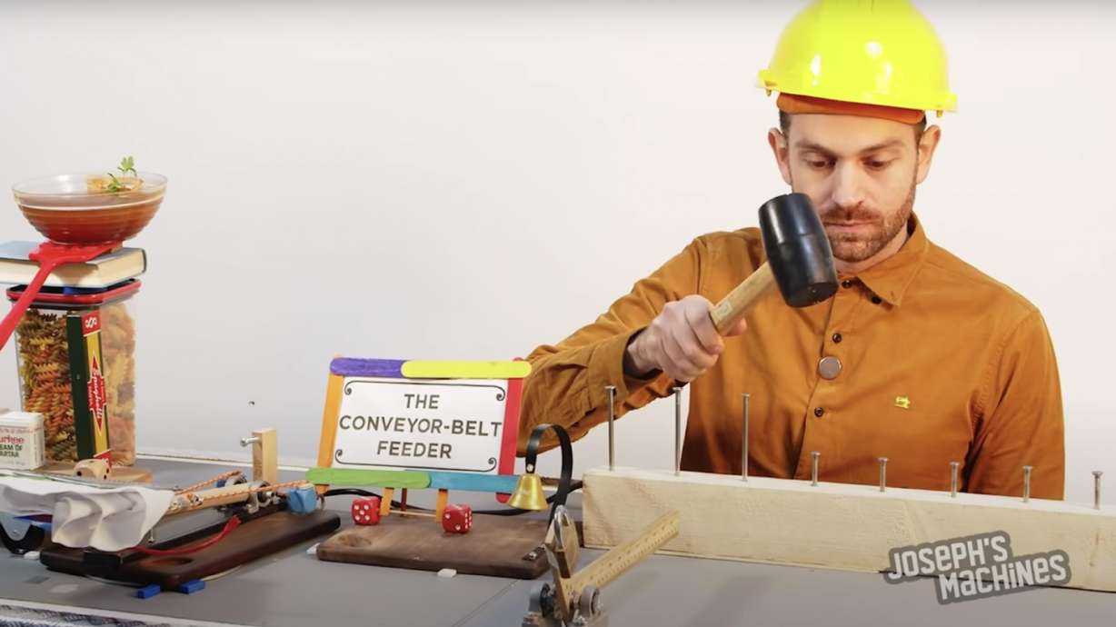 The machine tips, blows, and shoves food into his mouth as he tries to chew and swallow before the next course is forced into his gob.