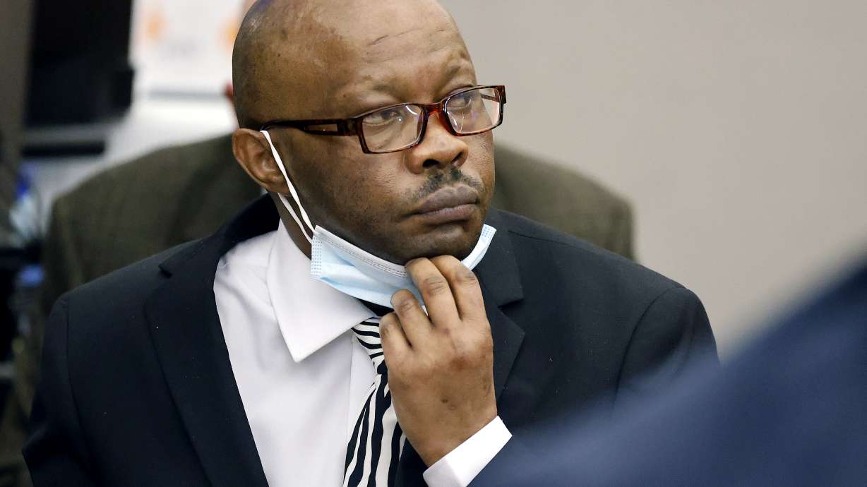 Defendant Billy Chemirmir lowers his mask as a state witness is asked to identify him during his murder trial at the Frank Crowley Courts Building in Dallas, Nov. 17, 2021. The retrial of the man charged with killing 18 older women in the Dallas area over a two-year span is set to begin Monday, after the first jury to hear a case against him deadlocked.
