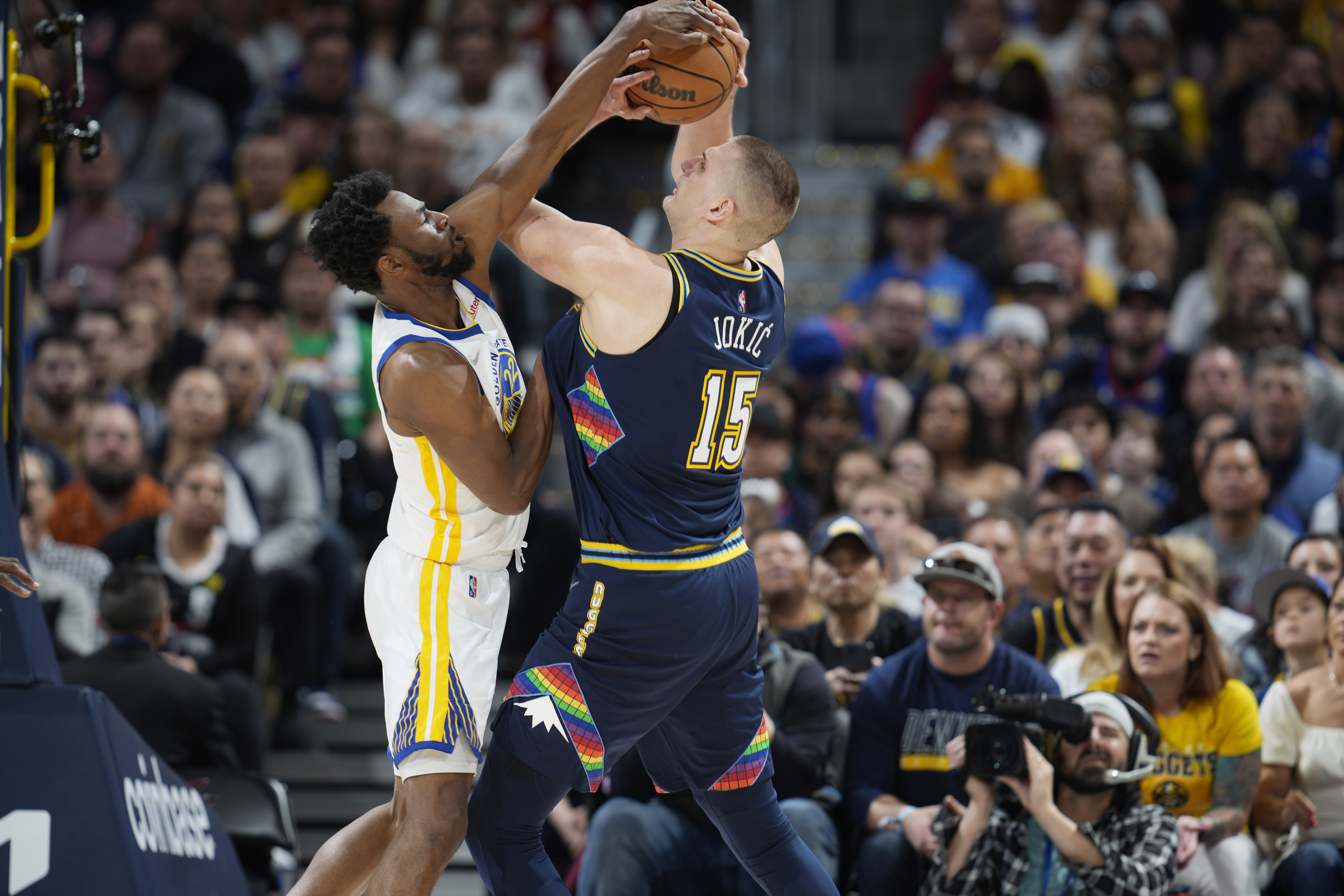 Golden State Warriors forward Andrew Wiggins, left, blocks a shot by Denver Nuggets center Nikola Jokic in the first half of Game 4 of an NBA basketball first-round Western Conference playoff series Sunday, April 24, 2022, in Denver. 