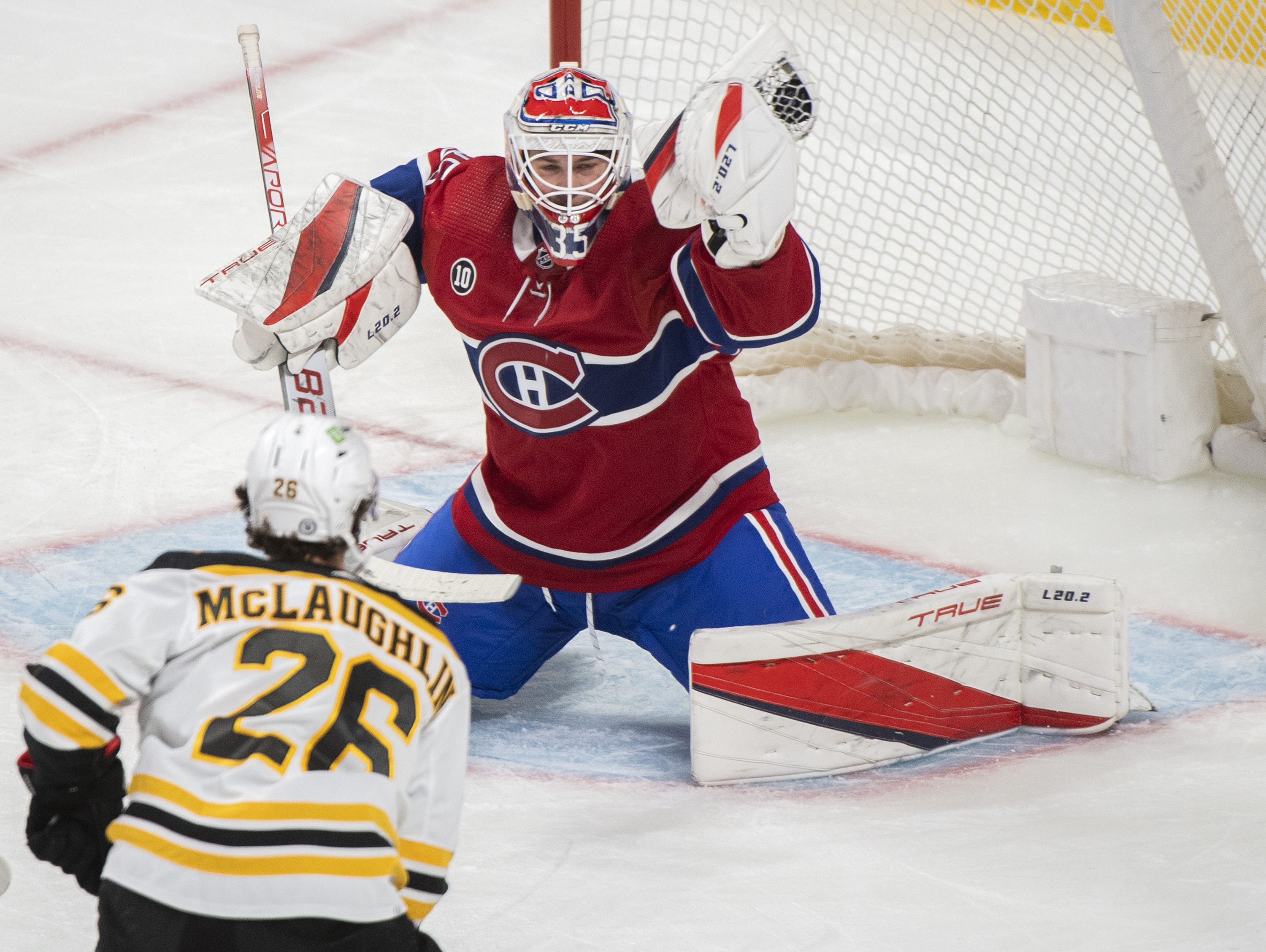 Montreal Canadiens goaltender Sam Montembeault, top, makes a save against Boston Bruins' Marc McLaughlin, bottom, during third-period NHL hockey game action in Montreal, Sunday, April 24, 2022. 
