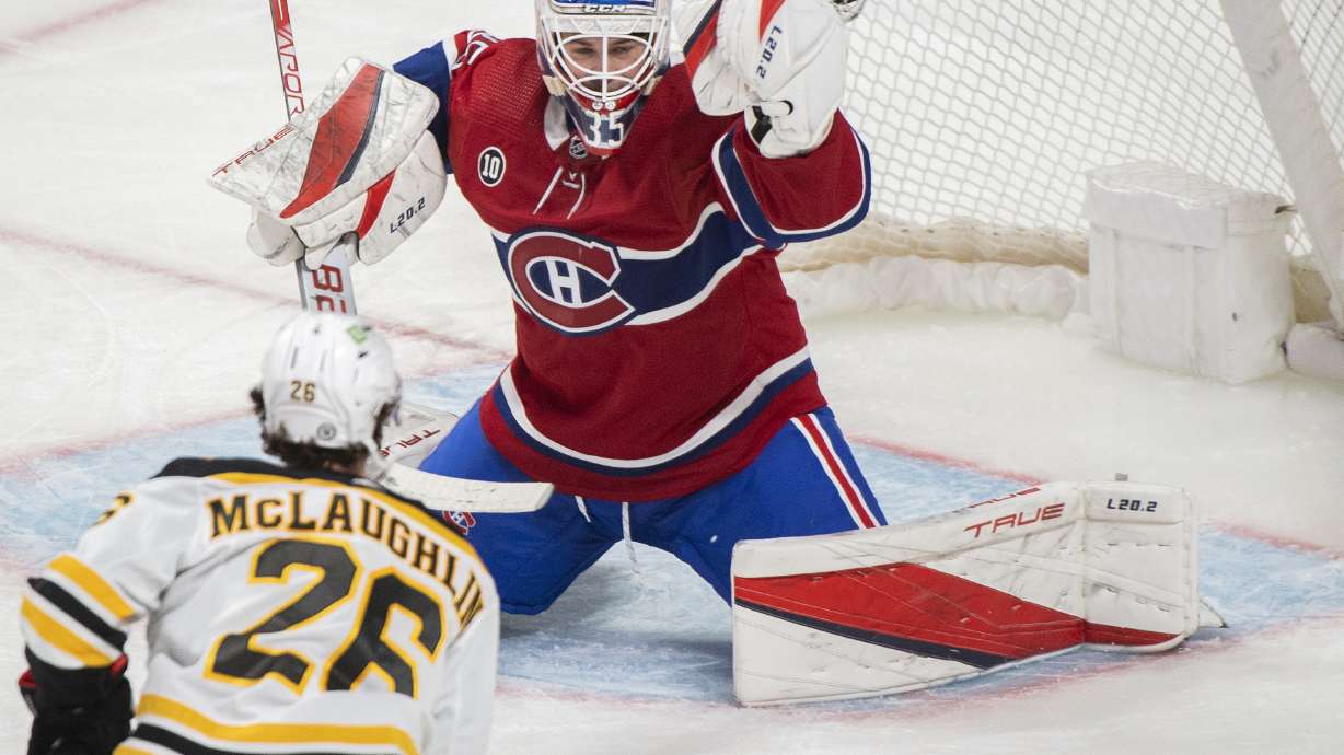 Montreal Canadiens goaltender Sam Montembeault, top, makes a save against Boston Bruins' Marc McLaughlin, bottom, during third-period NHL hockey game action in Montreal, Sunday, April 24, 2022.