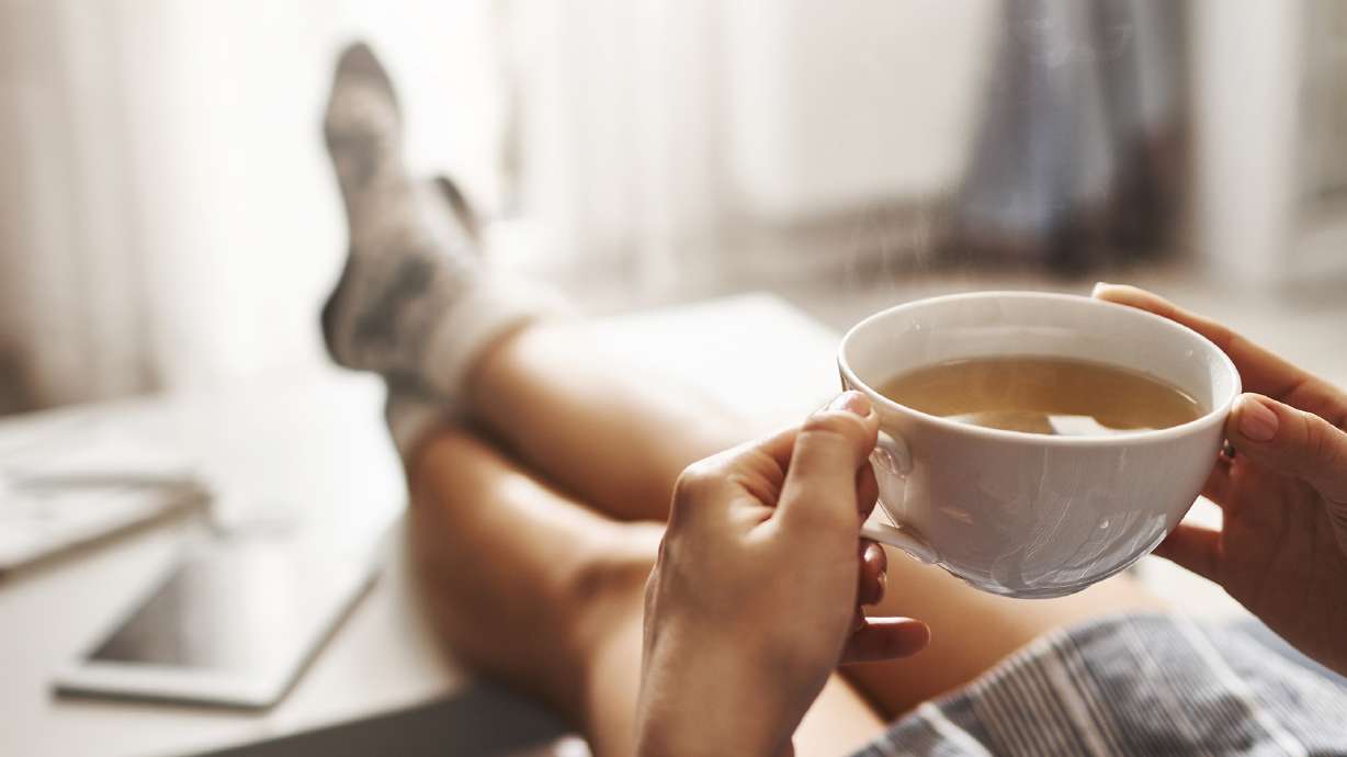 A woman drinks a cup of tea at home and relaxes.
