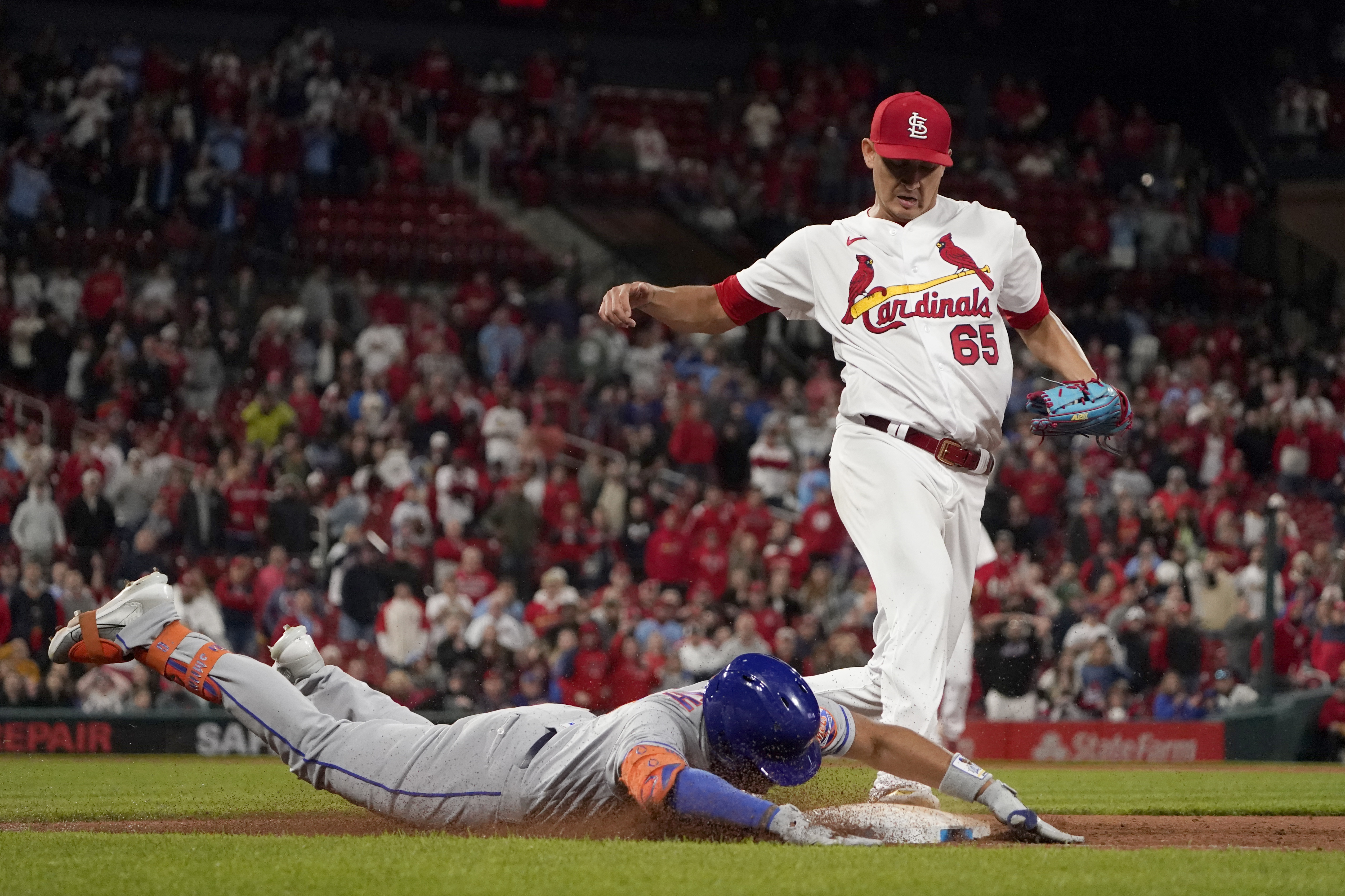 New York Mets' Dominic Smith is safe at first for a single as St. Louis Cardinals relief pitcher Giovanny Gallegos (65) is late to the bag during the ninth inning of a baseball game Monday, April 25, 2022, in St. Louis. The Mets' Travis Jankowski and Jeff McNeil scored on the play.
