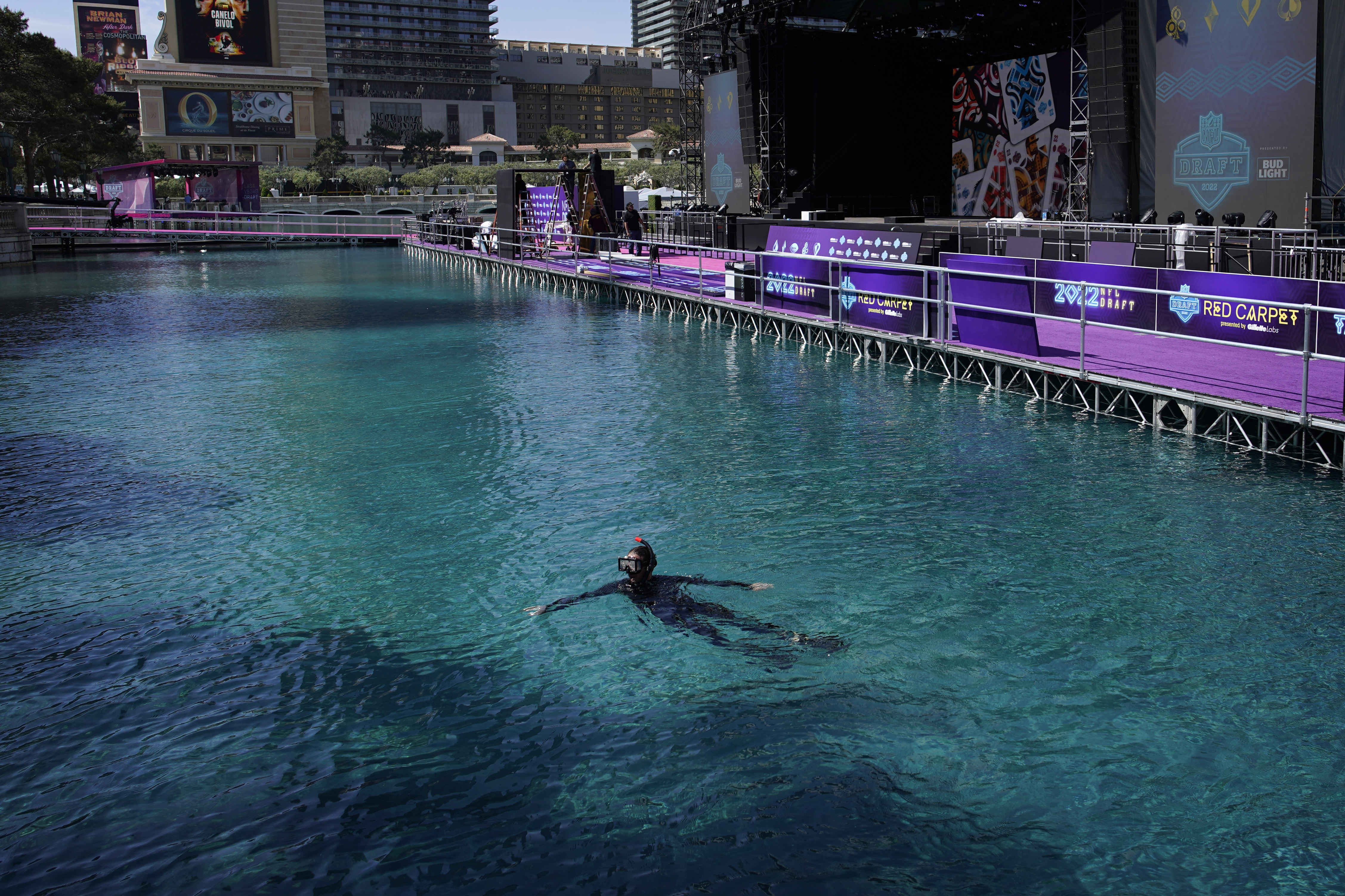 A worker swims in the fountain of the Bellagio hotel-casino during setup for the NFL football draft Tuesday, April 26, 2022, in Las Vegas. 