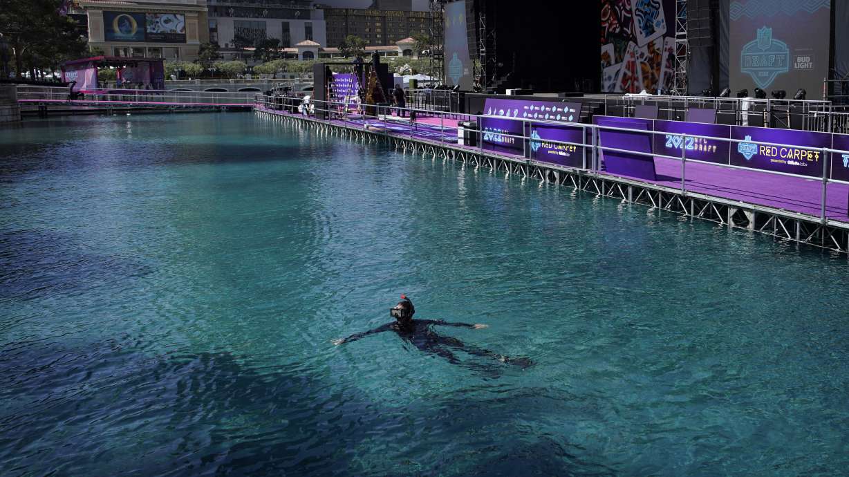 A worker swims in the fountain of the Bellagio hotel-casino during setup for the NFL football draft Tuesday, April 26, 2022, in Las Vegas.