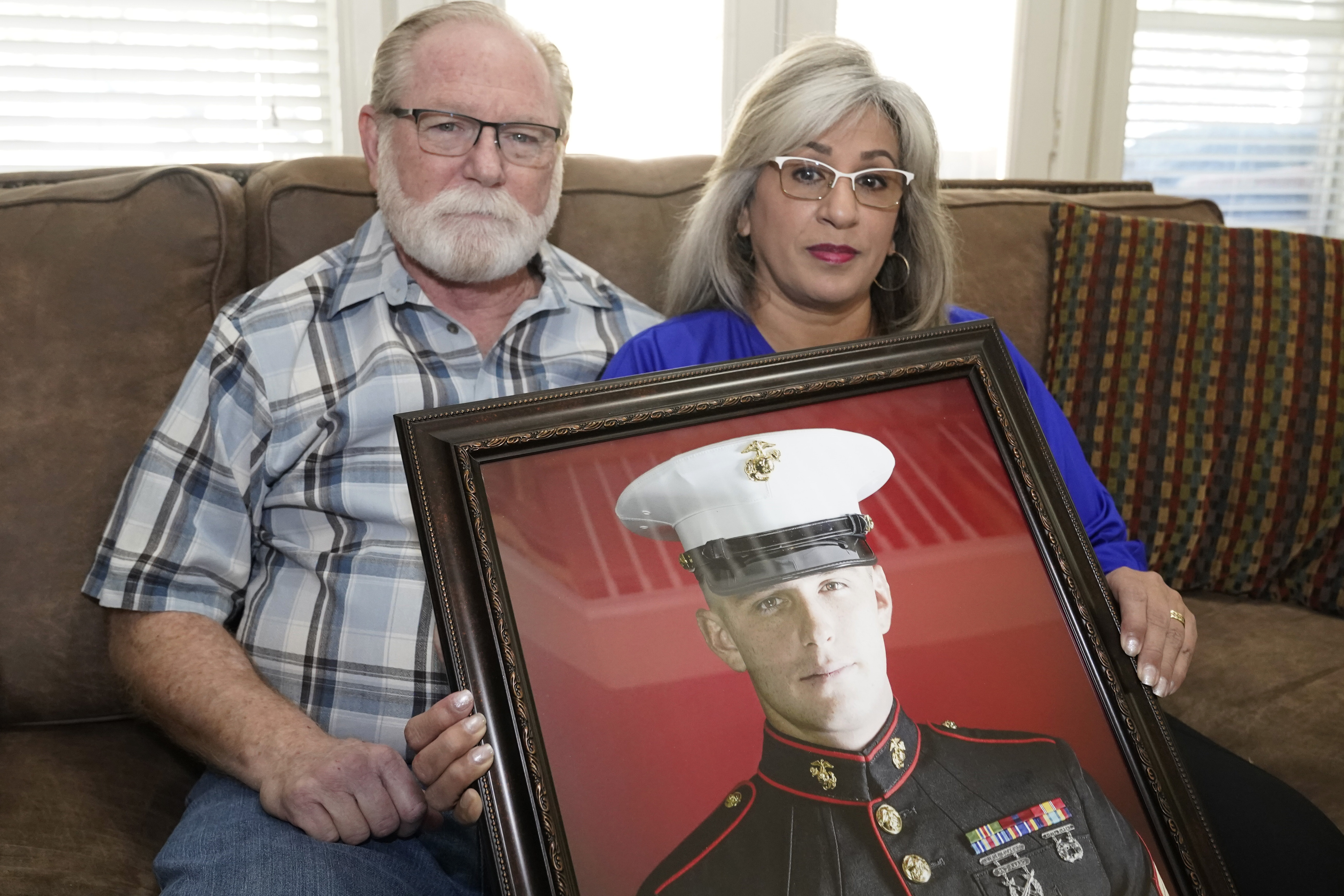 Joey and Paula Reed pose for a photo with a portrait of their son Marine veteran and Russian prisoner Trevor Reed at their home in Fort Worth, Texas, Feb. 15.