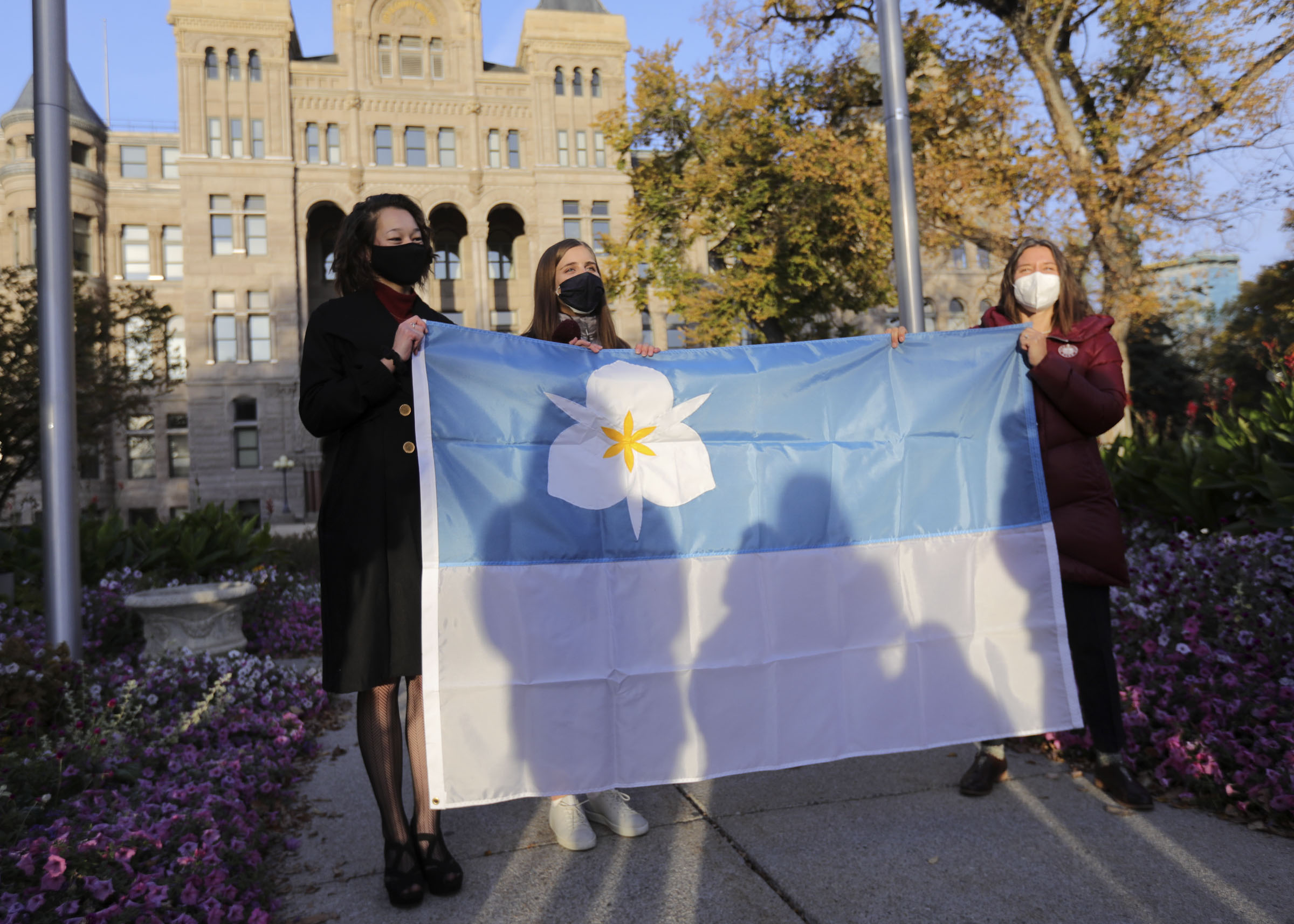 Ella Kennedy-Yoon, left, and Arianna Meinking, co-designers of Salt Lake City’s new flag, and Mayor Erin Mendenhall pose for a photo with the flag during a flag-raising ceremony outside of the City-County Building in Salt Lake City on Friday, Oct. 23, 2020. Kennedy-Yoon and Meinking’s submissions were selected separately and then their designs were combined to create the flag.