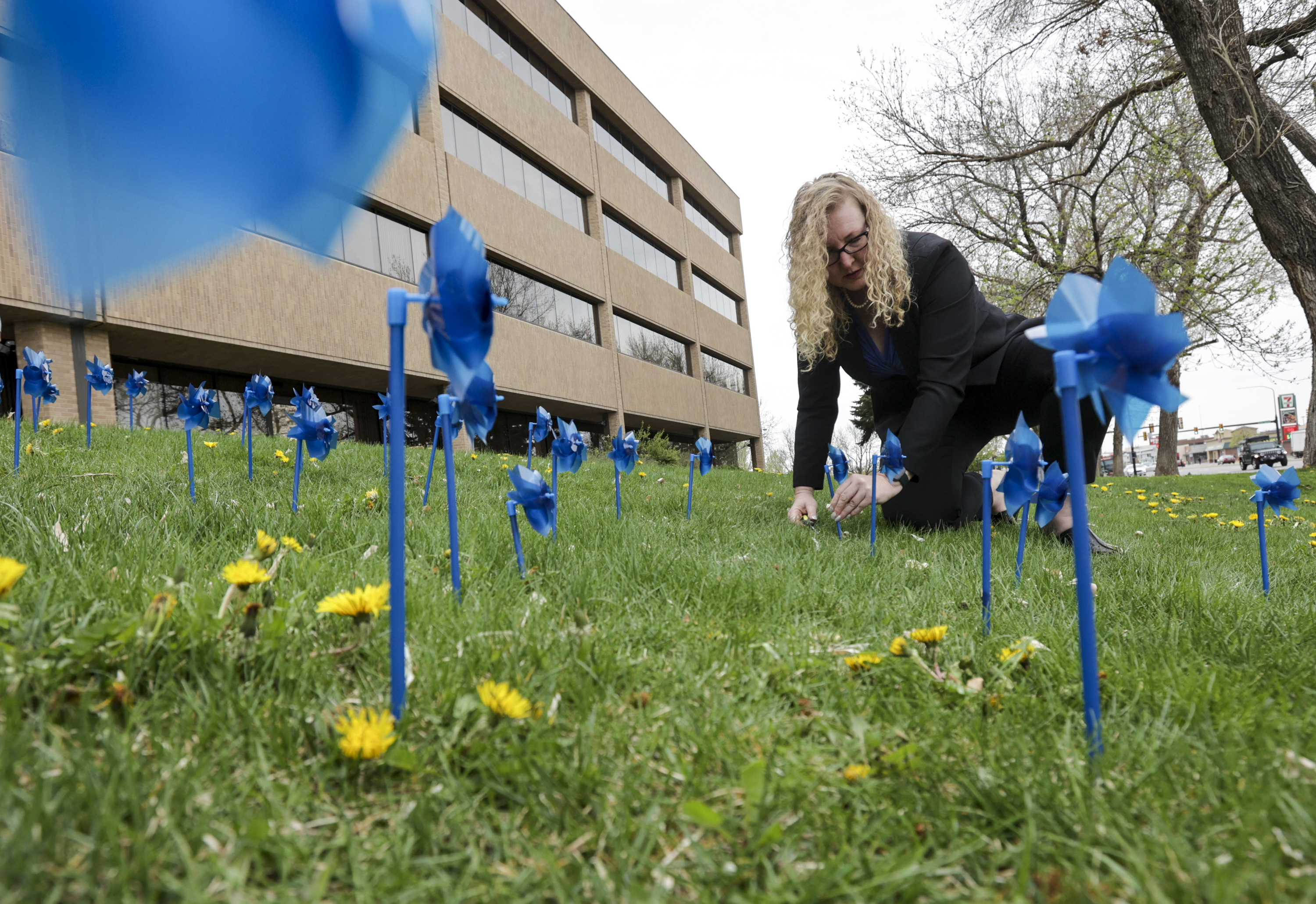 Laurie Stringham, chairwoman of Salt Lake County Council, plants blue pinwheels in honor of victims of child abuse at the Salt Lake County Government Center in Salt Lake City on Thursday.