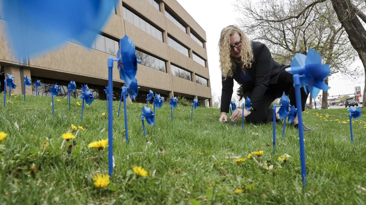 Laurie Stringham, chairwoman of Salt Lake County Council, plants blue pinwheels in honor of victims of child abuse at the Salt Lake County Government Center in Salt Lake City on Thursday.
