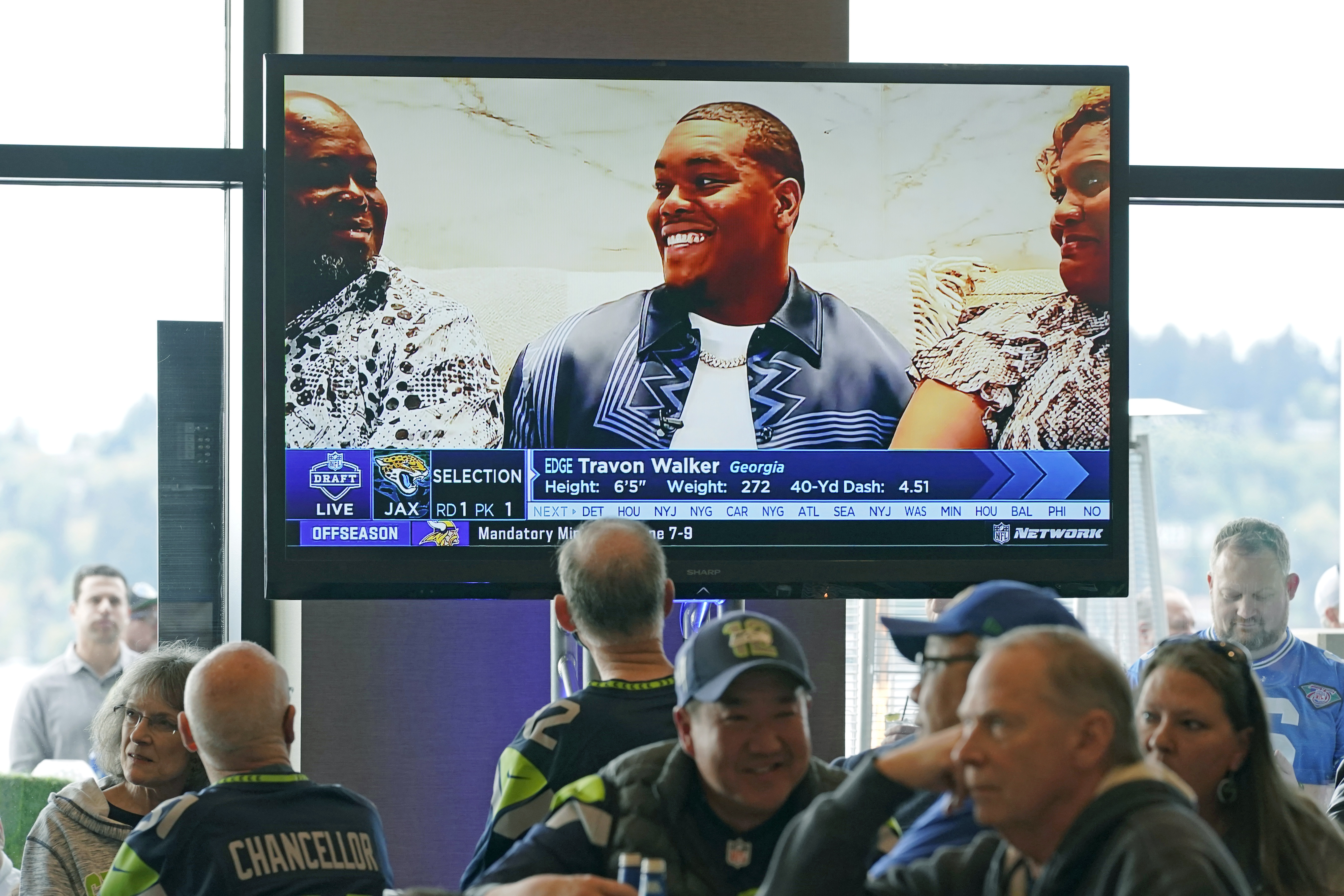 Seattle Seahawks fans watch as Georgia pass rusher Travon Walker is shown on a TV monitor as he is picked by the Jacksonville Jaguars as the top pick in the NFL football draft, Thursday, April 28, 2022, at a Seahawks draft day party in Renton, Wash., near Seattle.