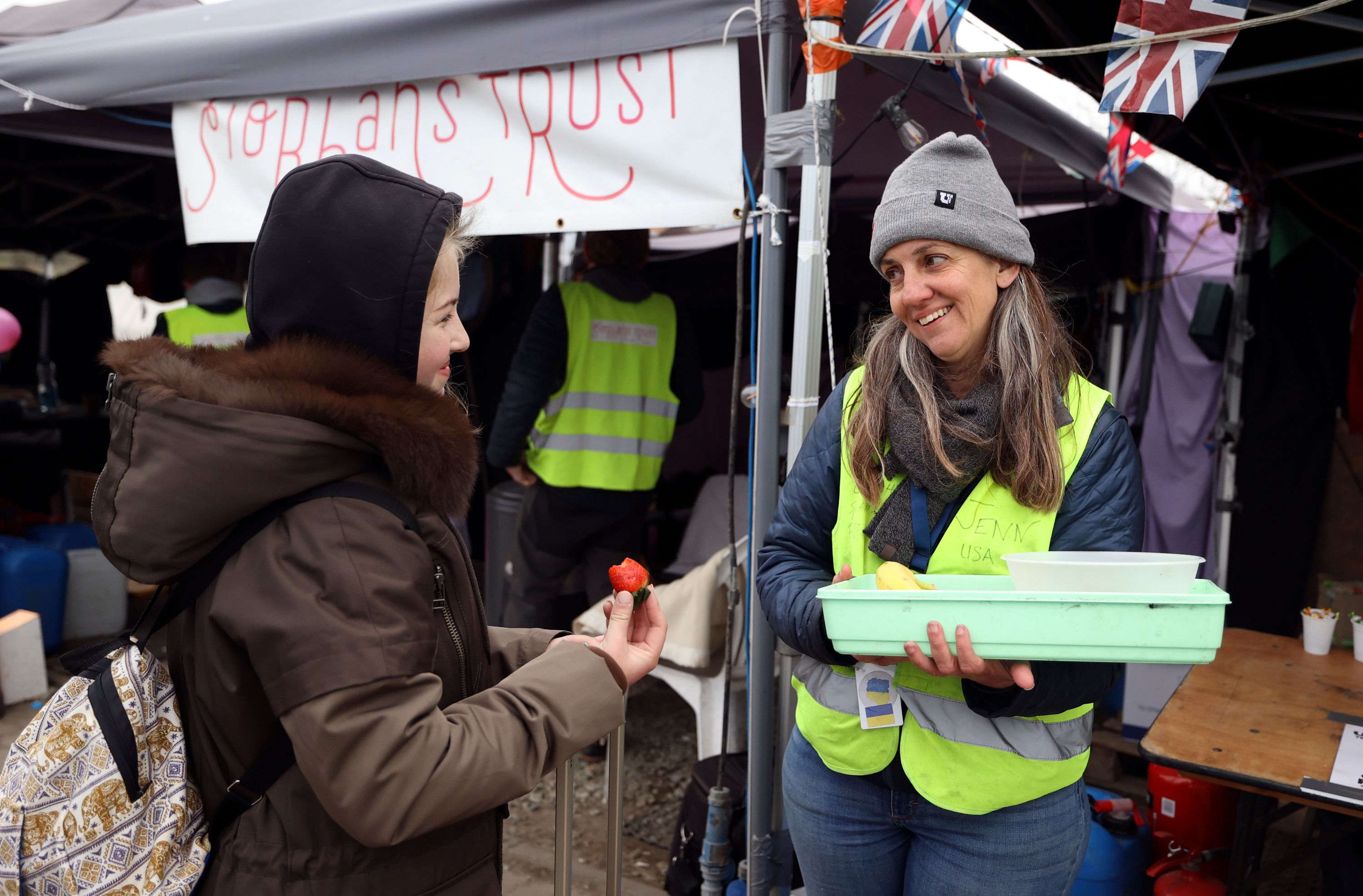 Volunteer Jennifer De Tapia, of Salt Lake City, right, gives strawberries to refugees passing the Siobhan’s Trust tent at the Polish-Ukrainian border in Medyka, Poland, April 21.