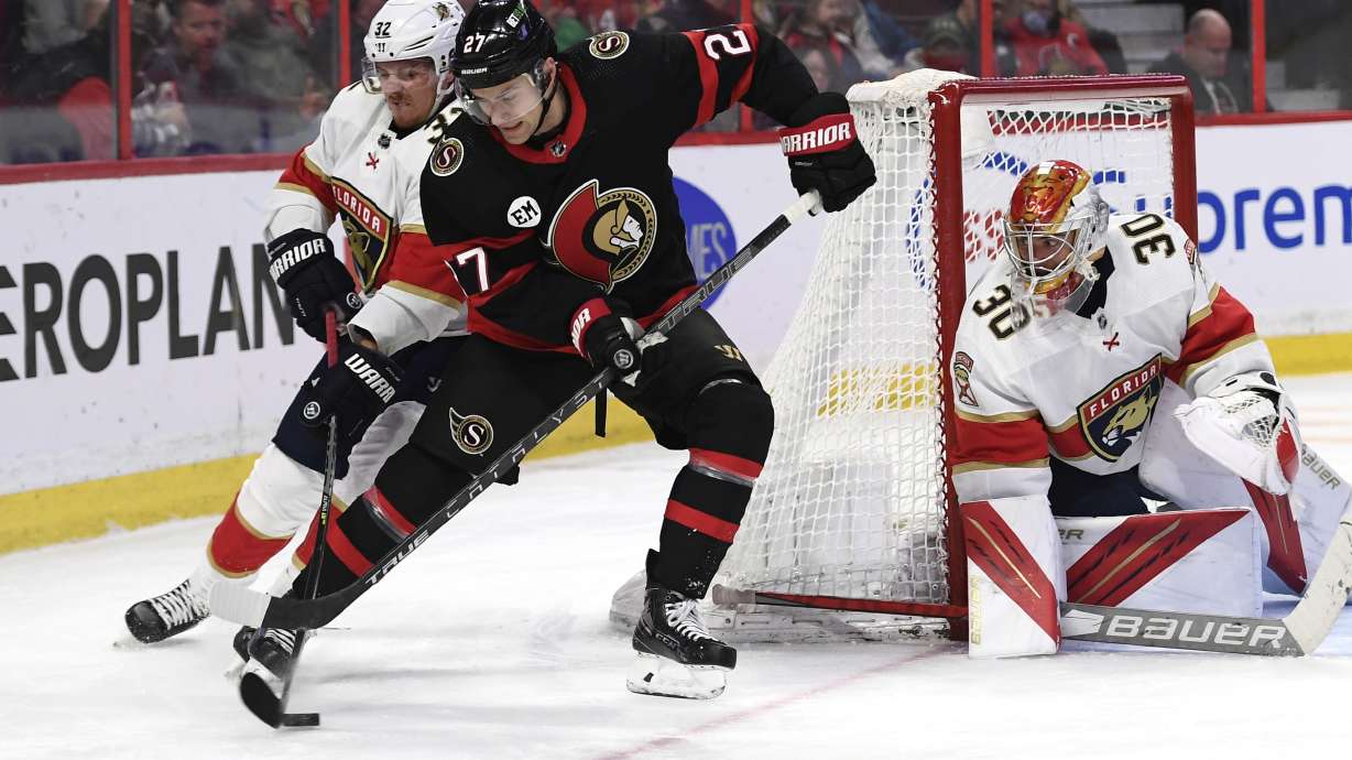 Florida Panthers defenceman Lucas Carlsson (32) passes the puck out of the reach of Ottawa Senators center Dylan Gambrell (27) as Panthers goaltender Spencer Knight (30) watches during the second period of an NHL hockey game Thursday, April 28, 2022, in Ottawa, Ontario.